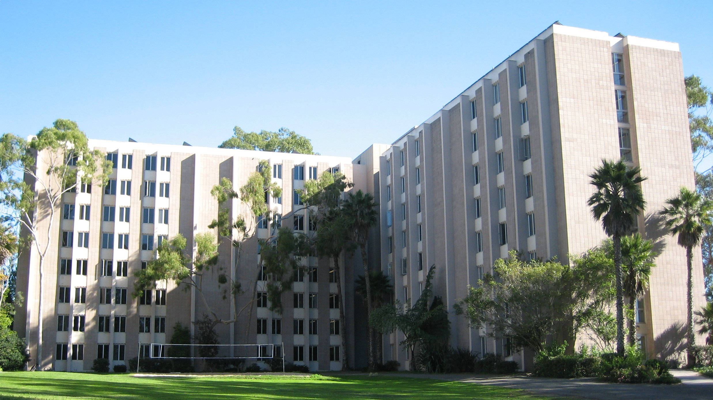 UCSB聖尼古拉斯宿舍 壁紙 — 一座大型米黃色大學宿舍樓，棕櫚樹和綠色草坪在晴朗的藍天下。