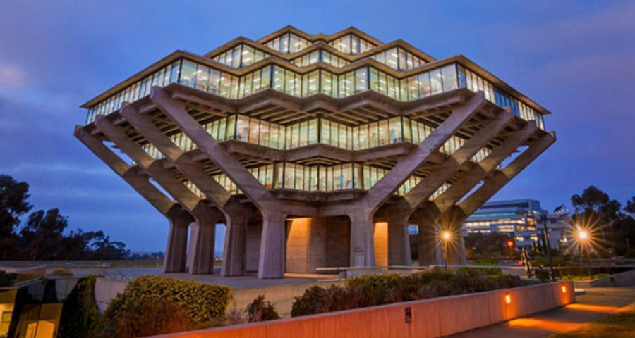 UCSD 早夜 壁紙 — 一座引人注目的幾何混凝土建築，帶有發光的玻璃窗，在暮色天空下亮起。