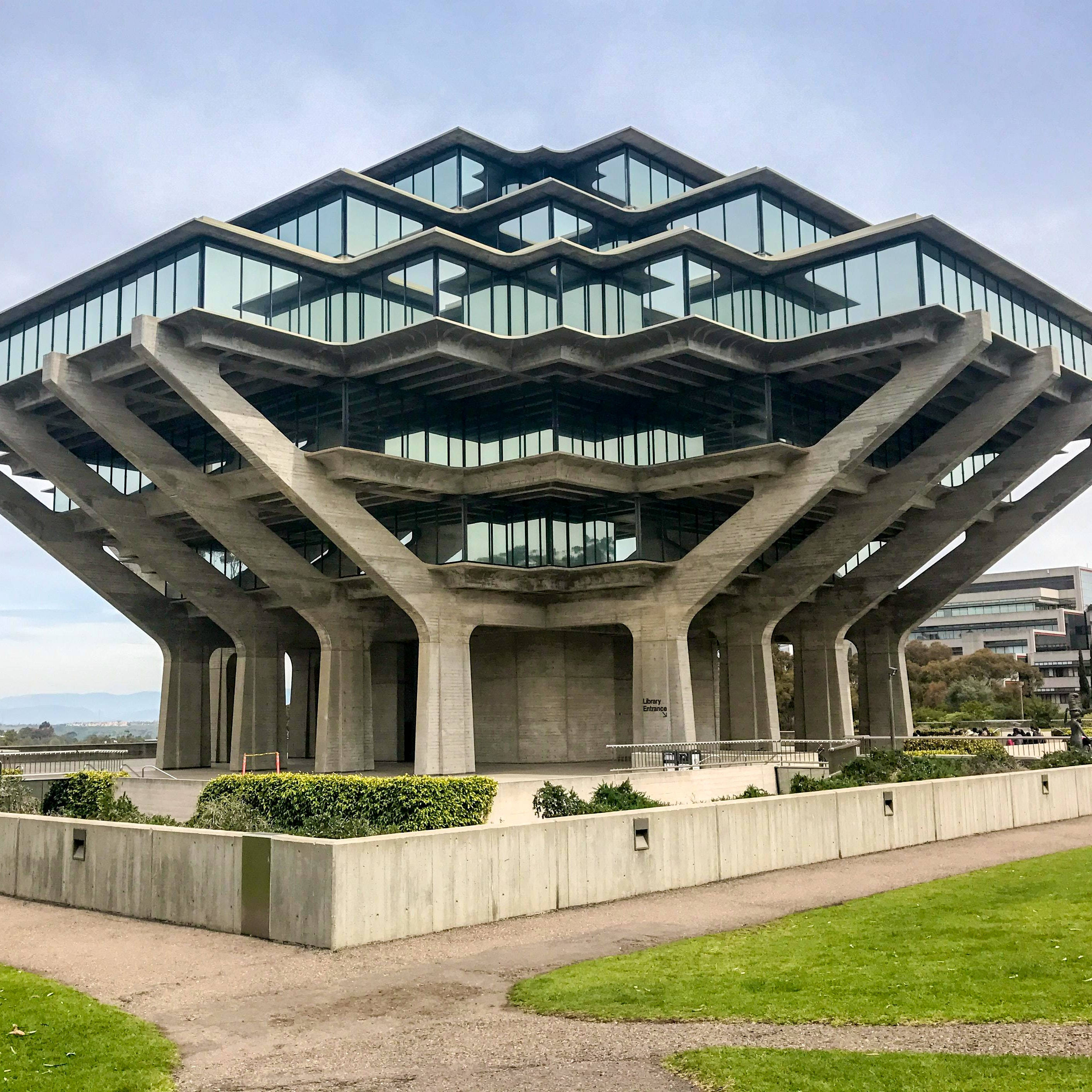 UCSD吉賽爾圖書館平板壁紙 壁紙 — 一座引人注目的粗獷主義圖書館，擁有分層混凝土支撐和玻璃幕牆，矗立在蒼白的天空下。