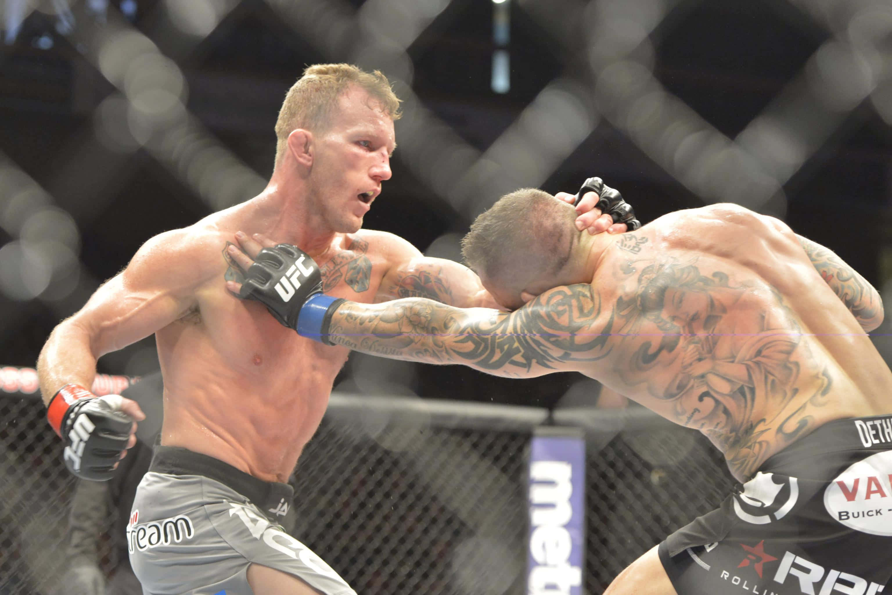 UFC 125: Resolution 格雷·梅納德對決Edgar 壁紙 — 兩名紋身MMA拳手在激烈的鐵籠賽中，汗水飛濺，表情兇猛。