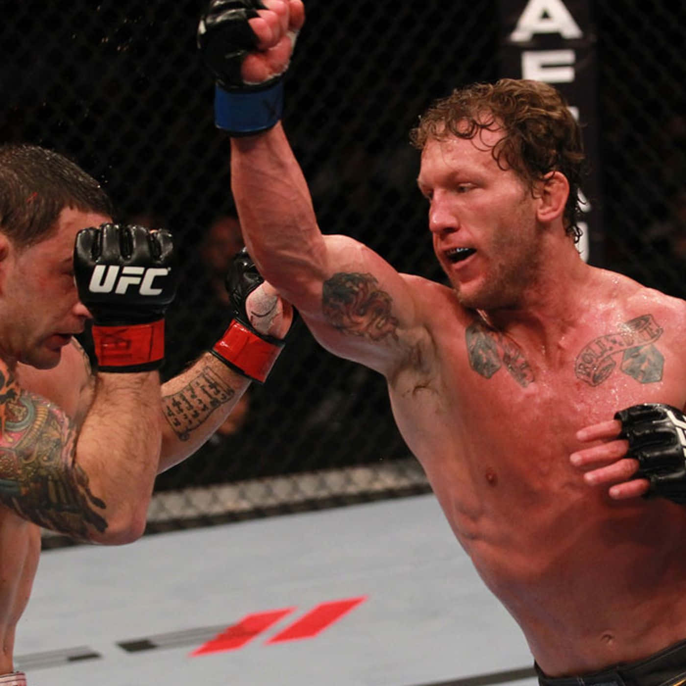 UFC 136：格雷·梅納德對戰弗蘭基·愛德加 壁紙 — 一位獲勝的綜合格鬥選手在UFC八角籠內高舉戴著手套的拳頭慶祝勝利，而他的對手則在旁觀看。
