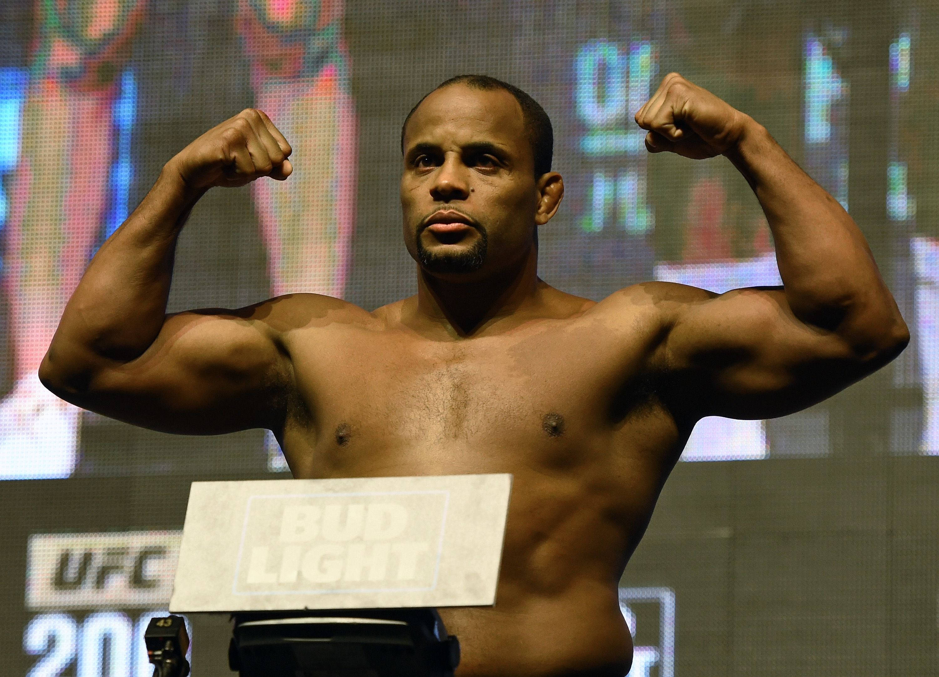 UFC On ESPN 7 丹尼爾·科爾米爾 壁紙 — 一位肌肉發達的UFC拳手在稱重活動中，於明亮的數碼屏幕前，在磅秤上屈起雙臂。