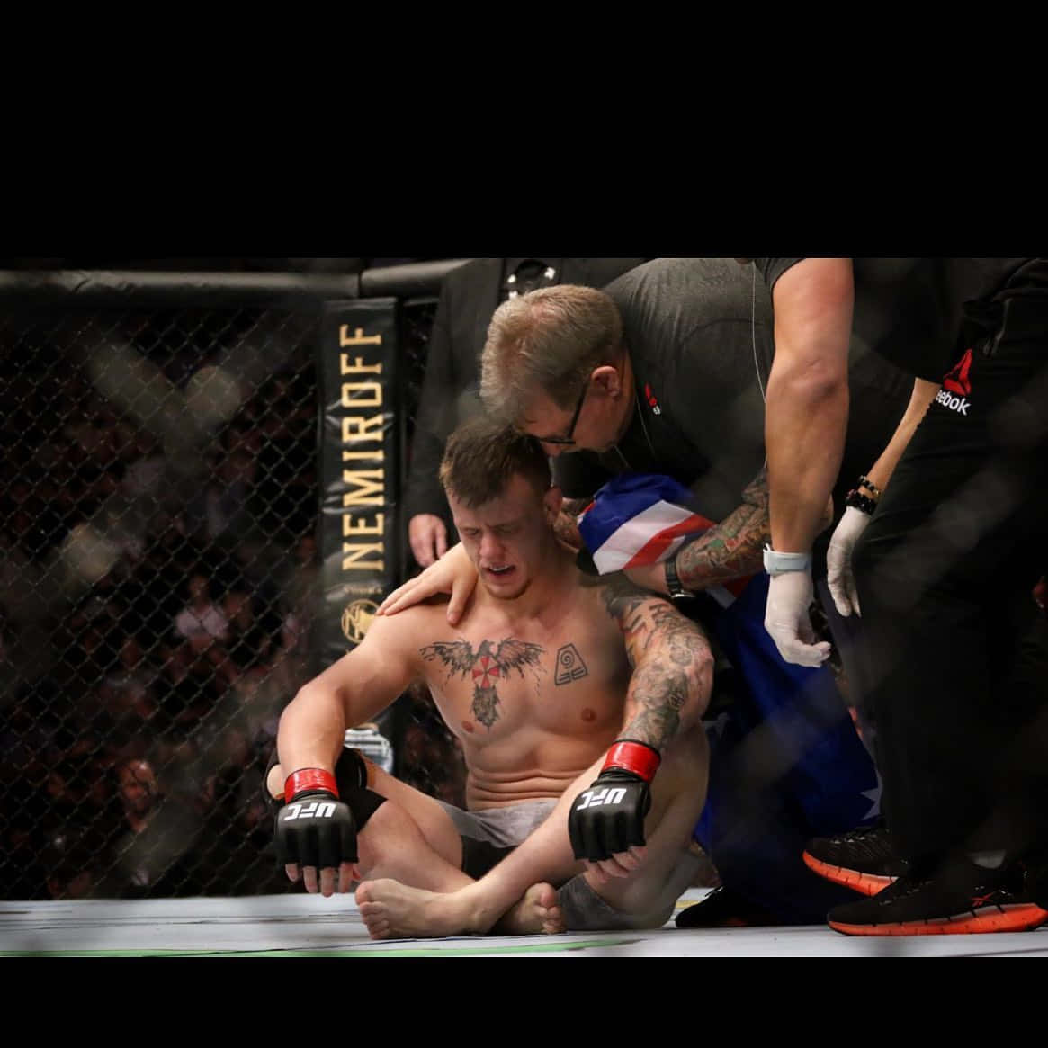 一名落敗的MMA拳手在八角籠內接受醫護人員治療。