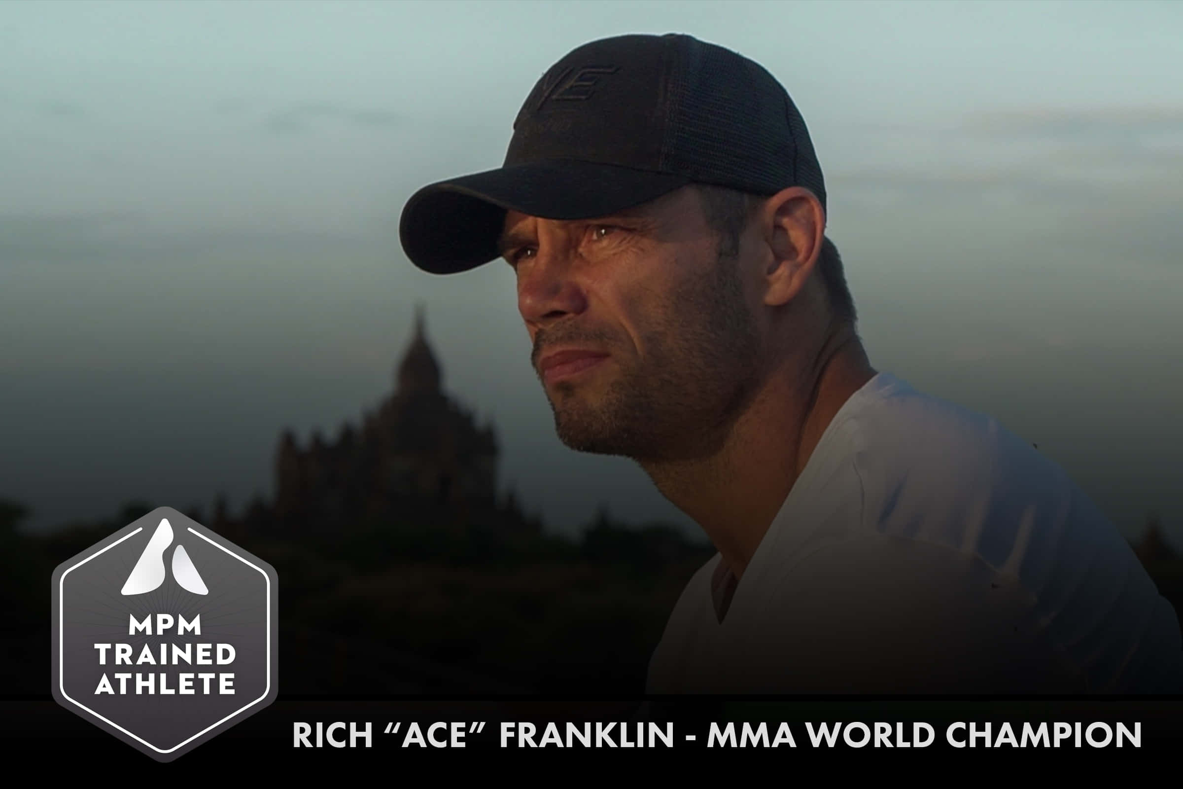 UFC中量級世界冠軍Rich Franklin 壁紙 — 一位專注的MMA冠軍戴著帽子，在暮色中若有所思地凝視著霧氣籠罩的寺廟輪廓。
