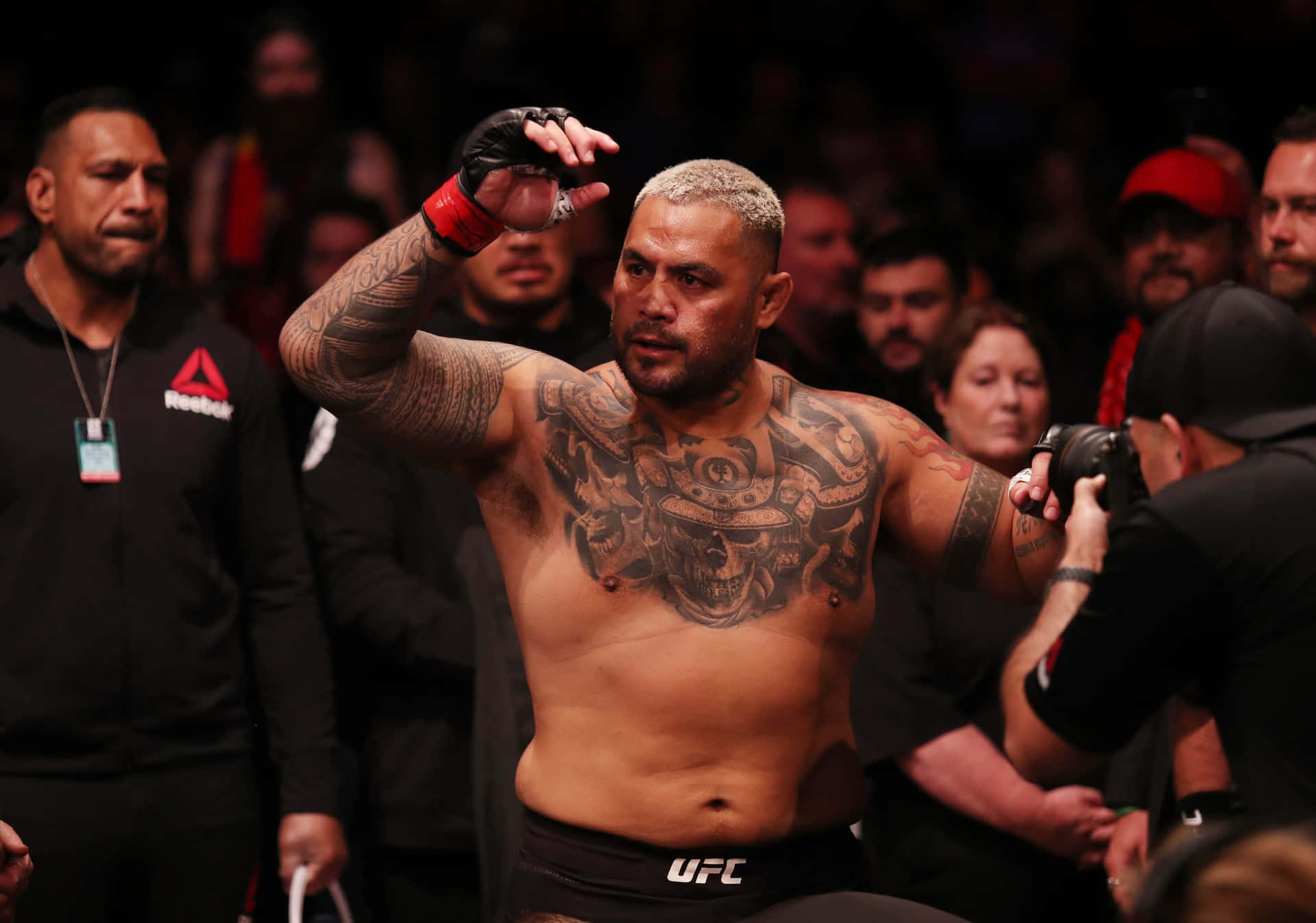 有紋身的MMA拳手在擠滿觀眾的場館中慶祝勝利。