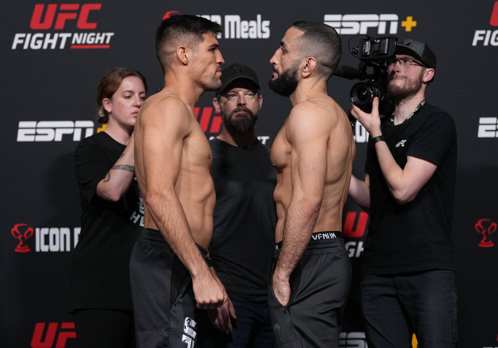 兩名男性UFC拳手在媒體和工作人員在場的稱重活動中對峙。