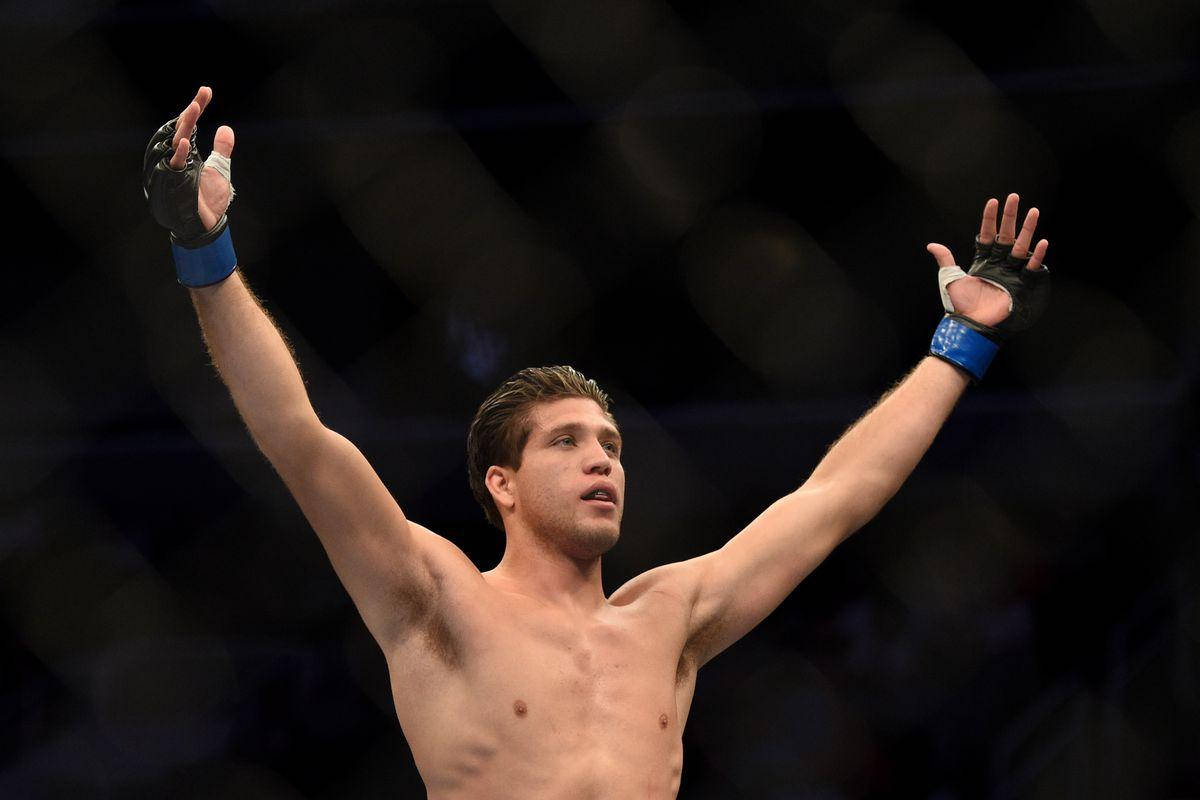 MMA選手在八角籠中高舉雙臂慶祝勝利。