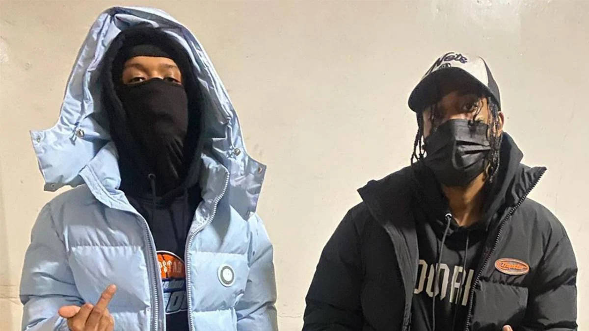 兩個人戴著口罩和冬季外套，室內站立。