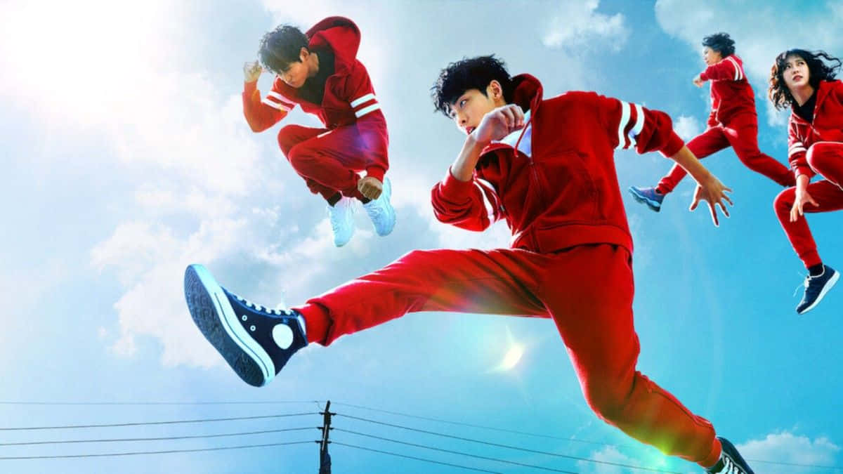 四名身穿紅色運動服的青少年在藍天白雲中凌空跳躍。
