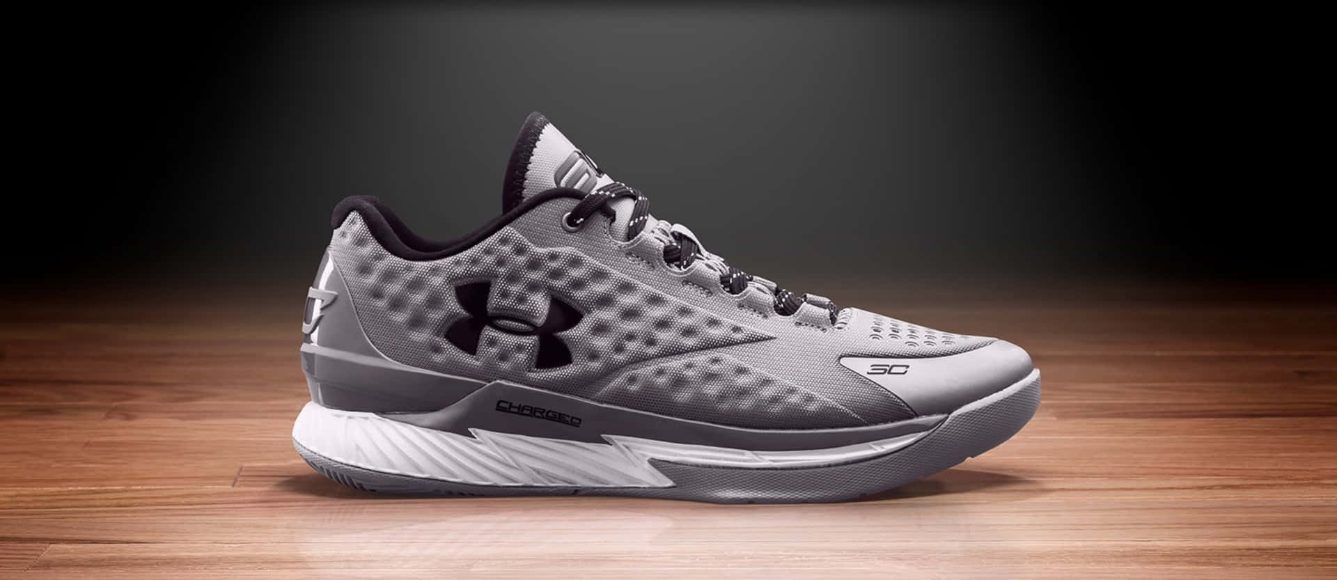 灰色 Under Armour 籃球鞋在木地板上，工作室燈光。