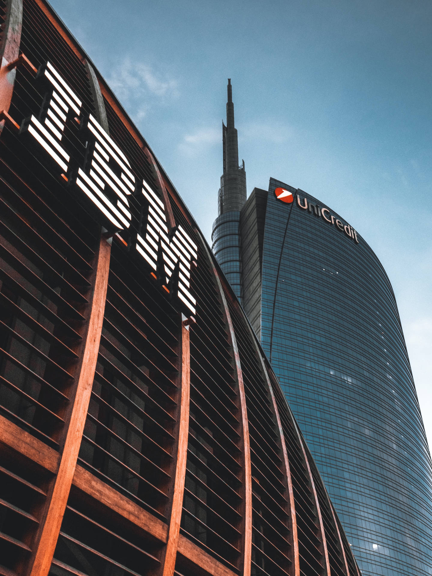 清澈藍天下，帶有IBM和UniCredit標誌的現代企業摩天大樓。
