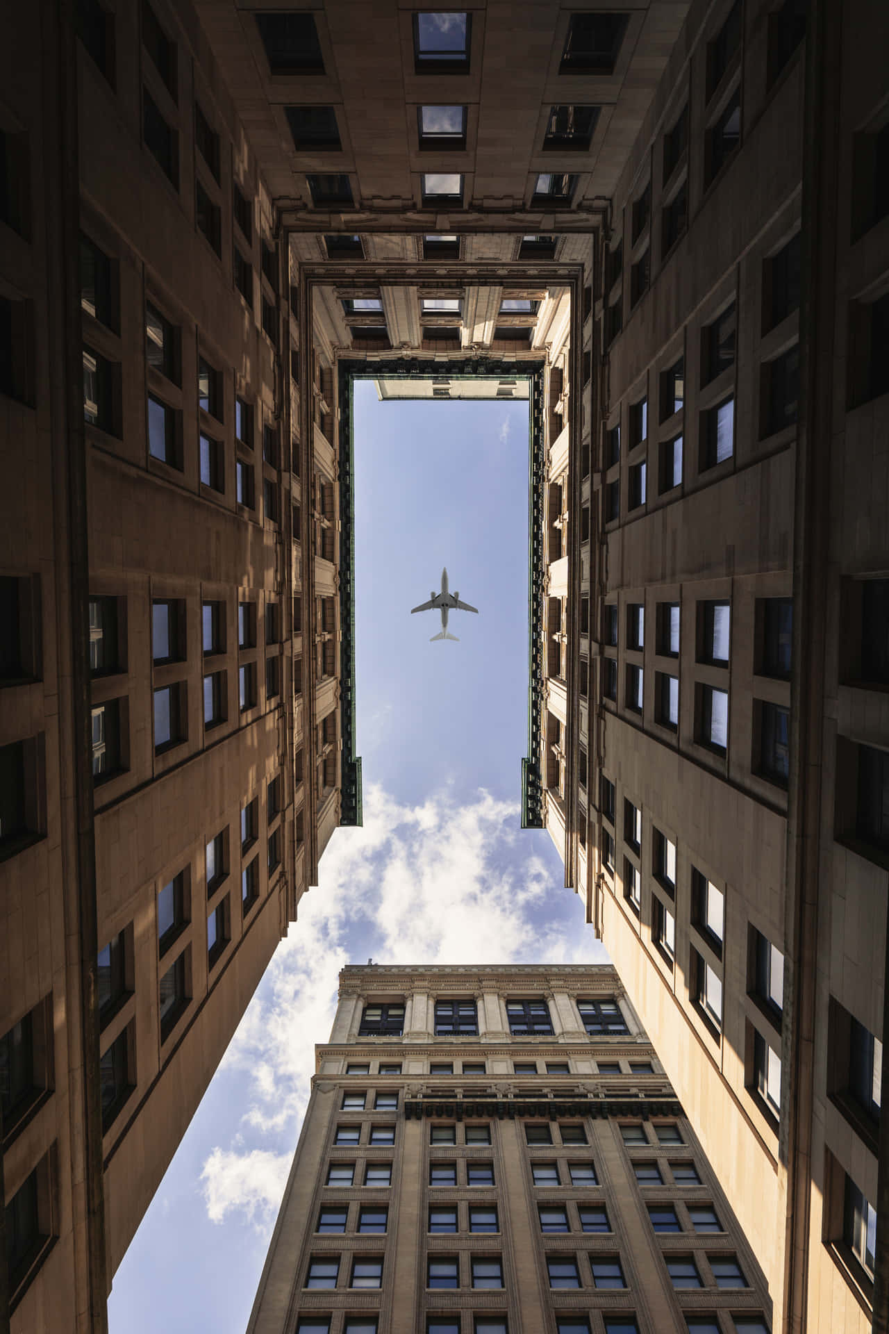 一架飛機在城市峽谷中高聳的石建築之間飛行。