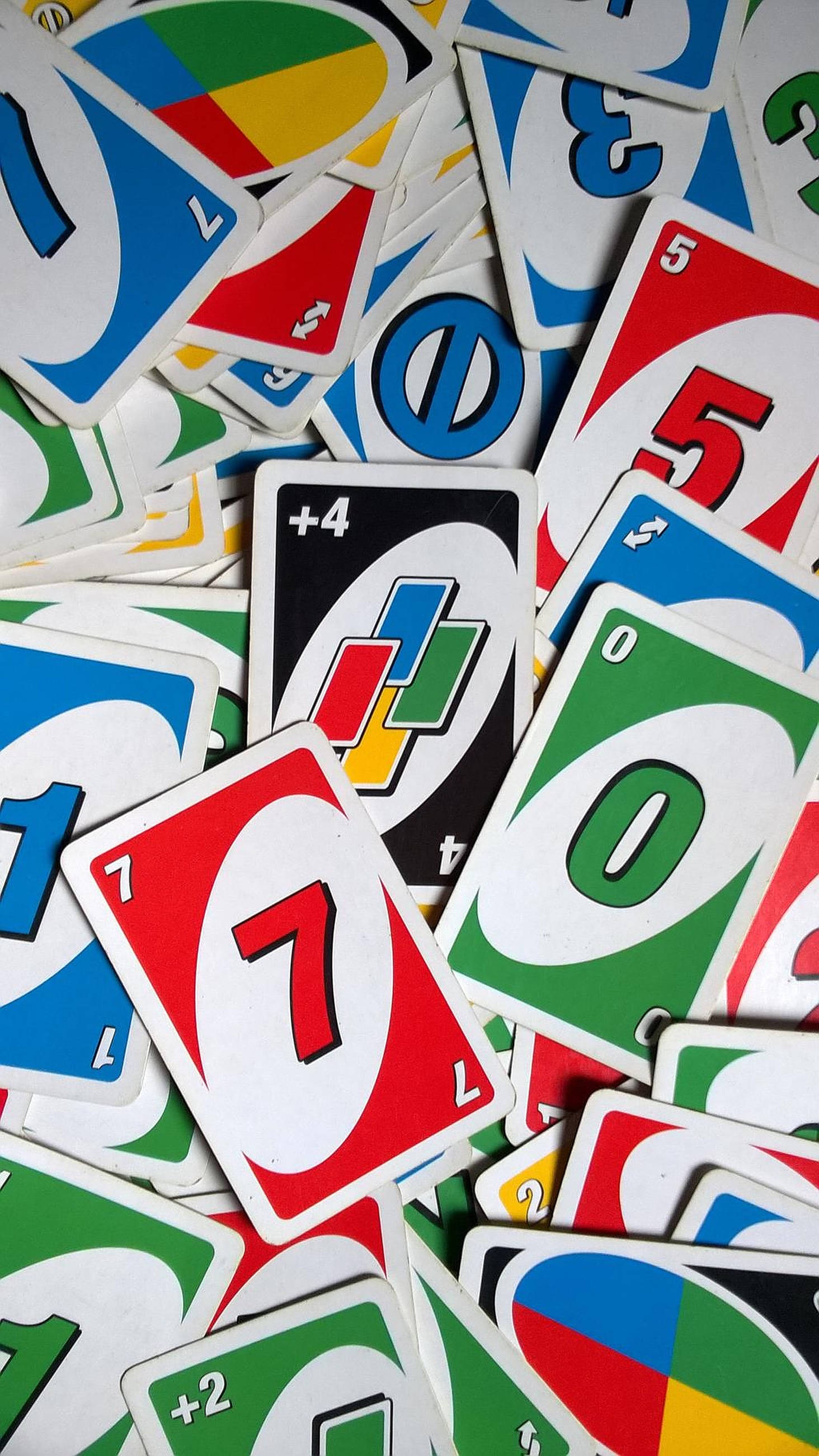 Uno 卡牌組 壁紙 — 一堆色彩繽紛混亂的Uno卡，上面有數字和特別行動符號，以粗體的紅、藍、綠、黃色呈現。