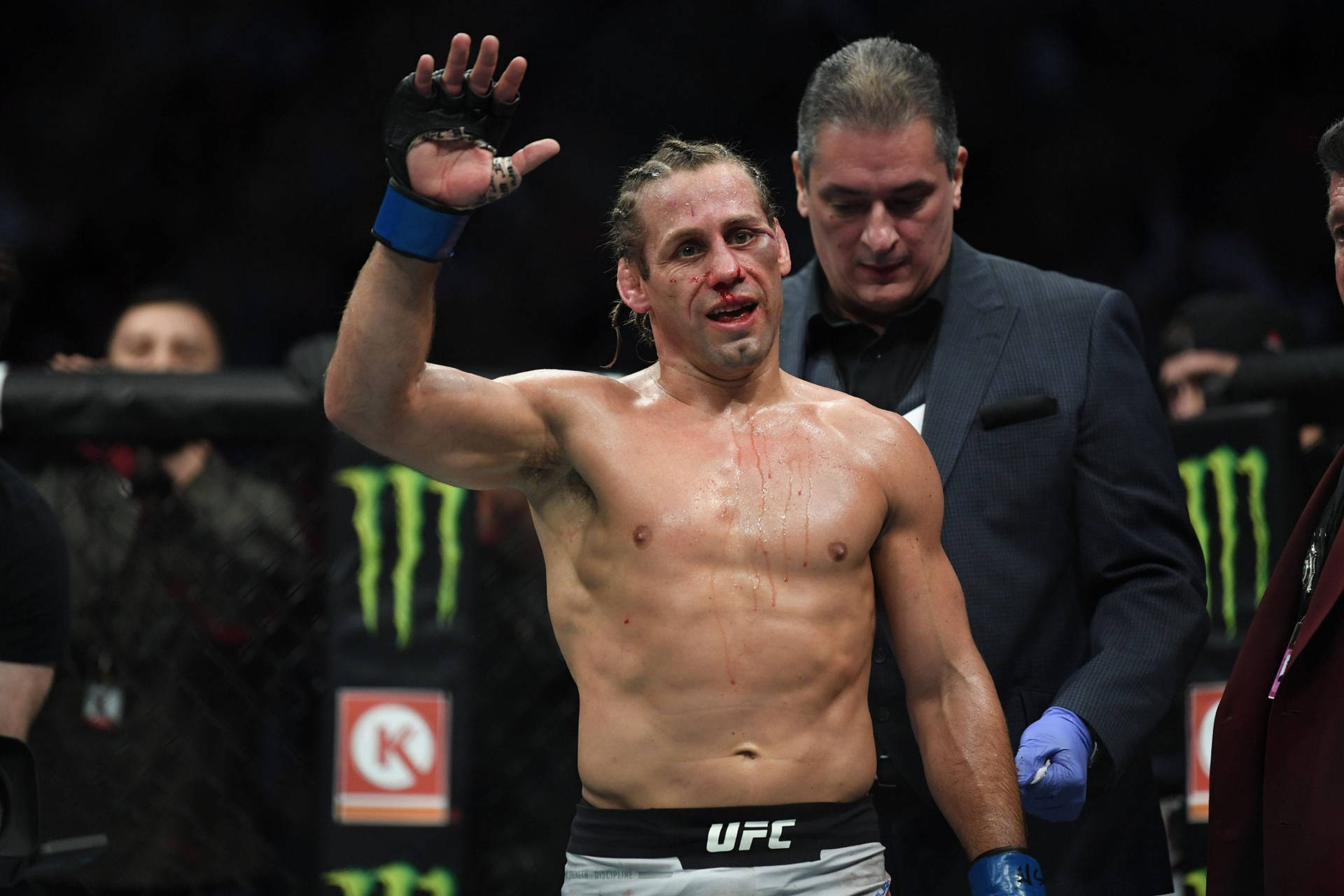 一名滿臉鮮血的勝利MMA拳手在UFC八角籠內向人群揮手。