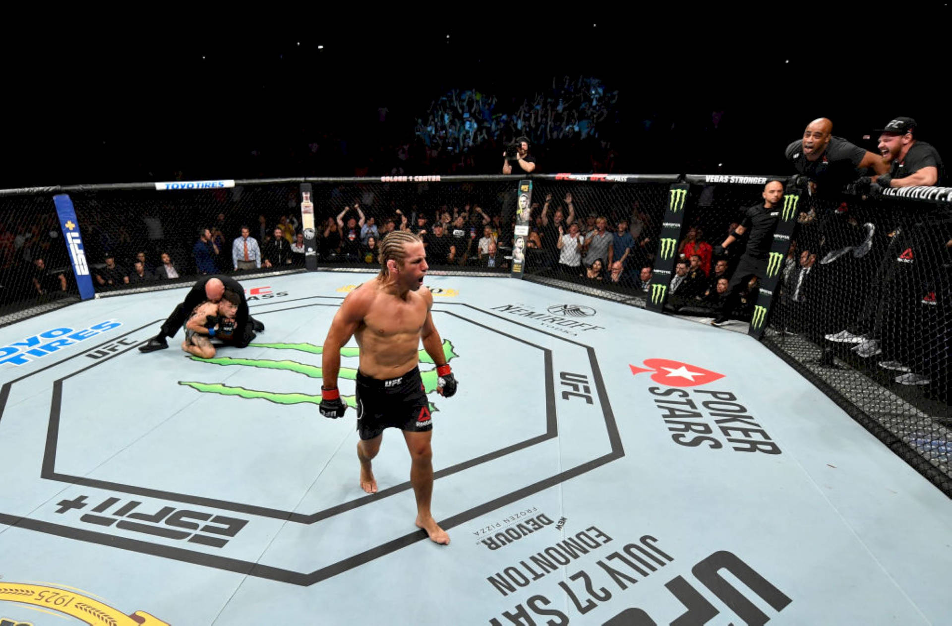 UFC拳手在八角籠中慶祝勝利，觀眾歡呼。