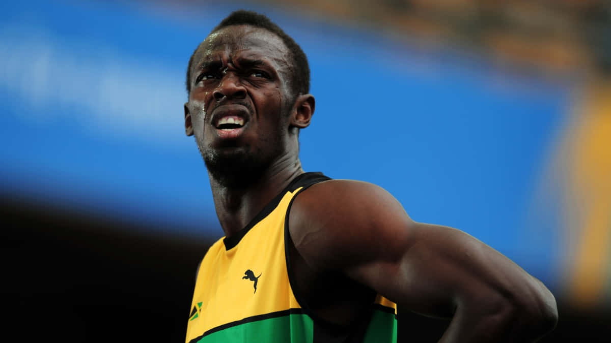 Usain Bolt 瞪眼表情 壁紙 — 身穿黃綠色球衣的運動員在體育場燈光下比賽時，表情痛苦地扭曲。