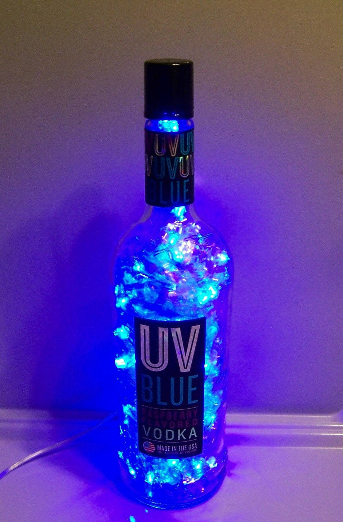 一個用藍色仙女燈照亮的伏特加酒瓶，散發出紫色光芒。