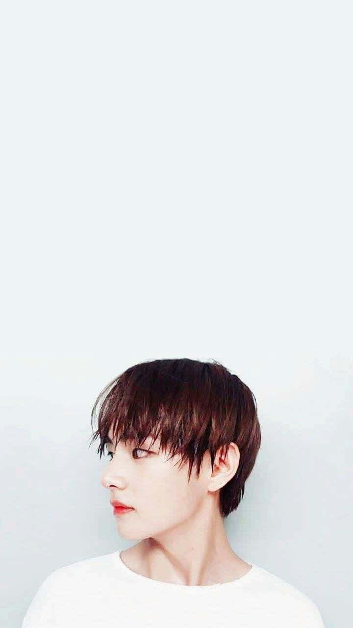 V BTS 側臉濕髮手機壁紙 壁紙 — 一位短黑髮紅唇的年輕人，在純淺灰色背景前若有所思地凝視。