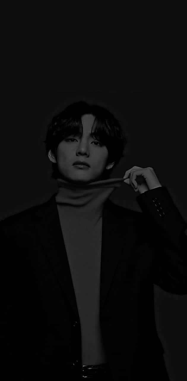 V BTS 手機暗黑模式 壁紙 — 一個穿著高領毛衣和西裝外套的年輕男子在深色背景下的單色肖像。