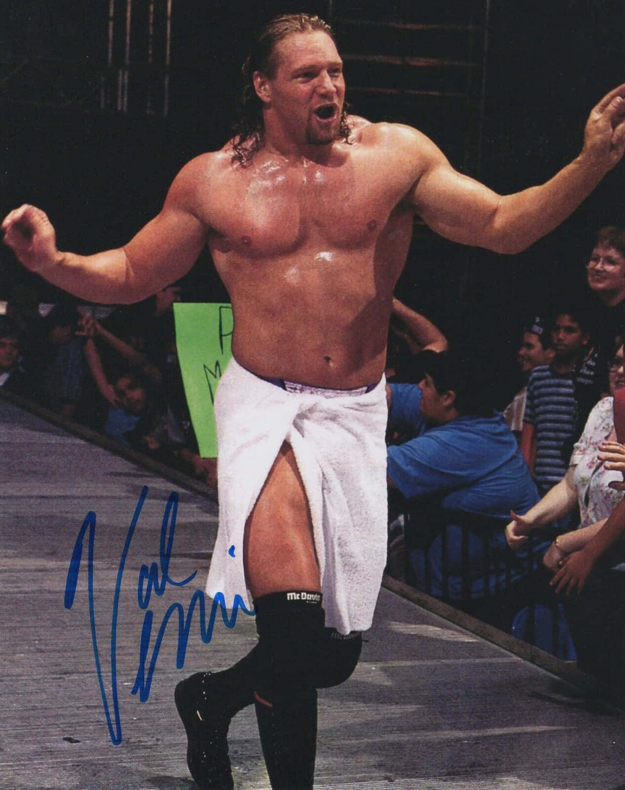 加拿大退役職業摔角手 Val Venis 壁紙 — 一位肌肉發達、長髮、腰間圍著白色毛巾的摔角手，在擂台上興奮地慶祝勝利，身後是熱情的觀眾。