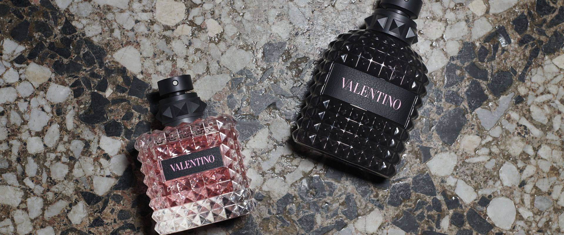 Valentino香水瓶排列 壁紙 — 兩瓶 Valentino 香水，一瓶透明切割粉紅色，一瓶黑色鉚釘裝飾，放在斑點石面上。