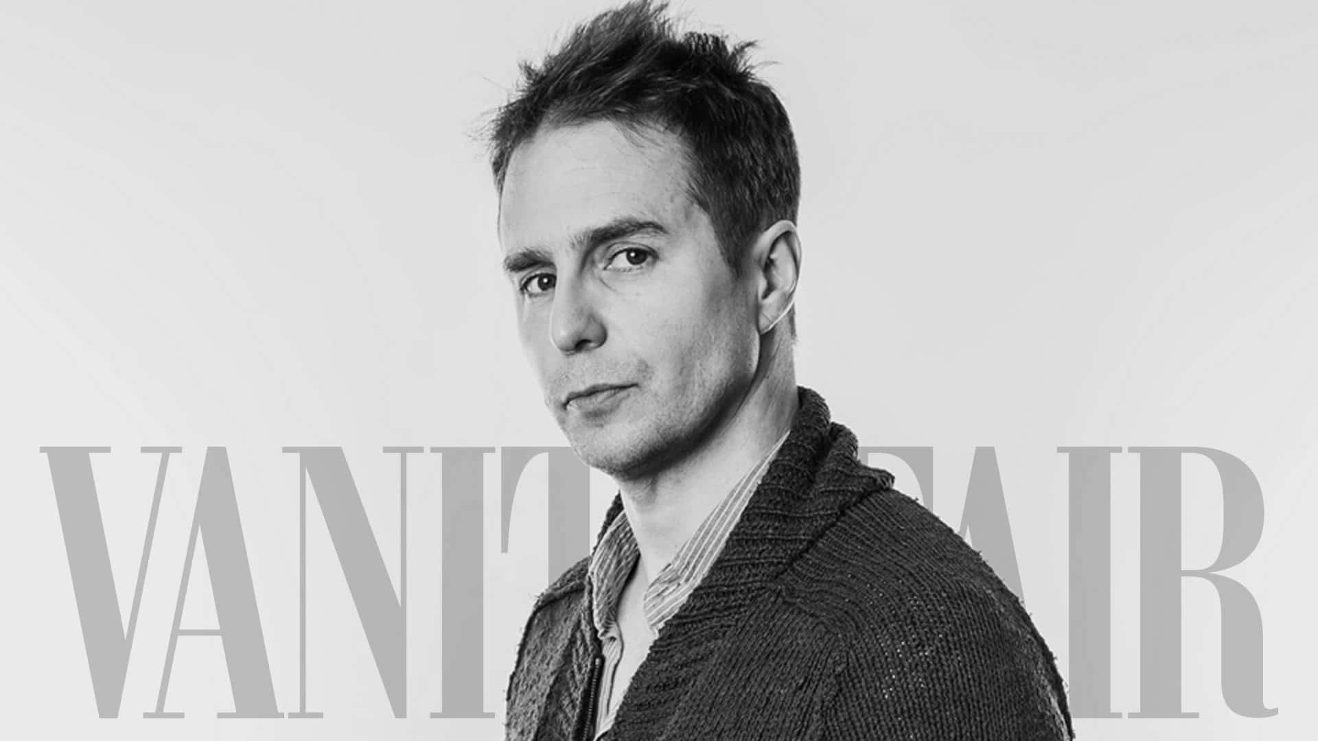 山姆·洛克韋爾《Vanity Fair》時尚拍攝 壁紙 — 一個穿著質感開襟衫的男人在純色背景上的黑白肖像，帶有 'VANITY FAIR' 文字疊加。