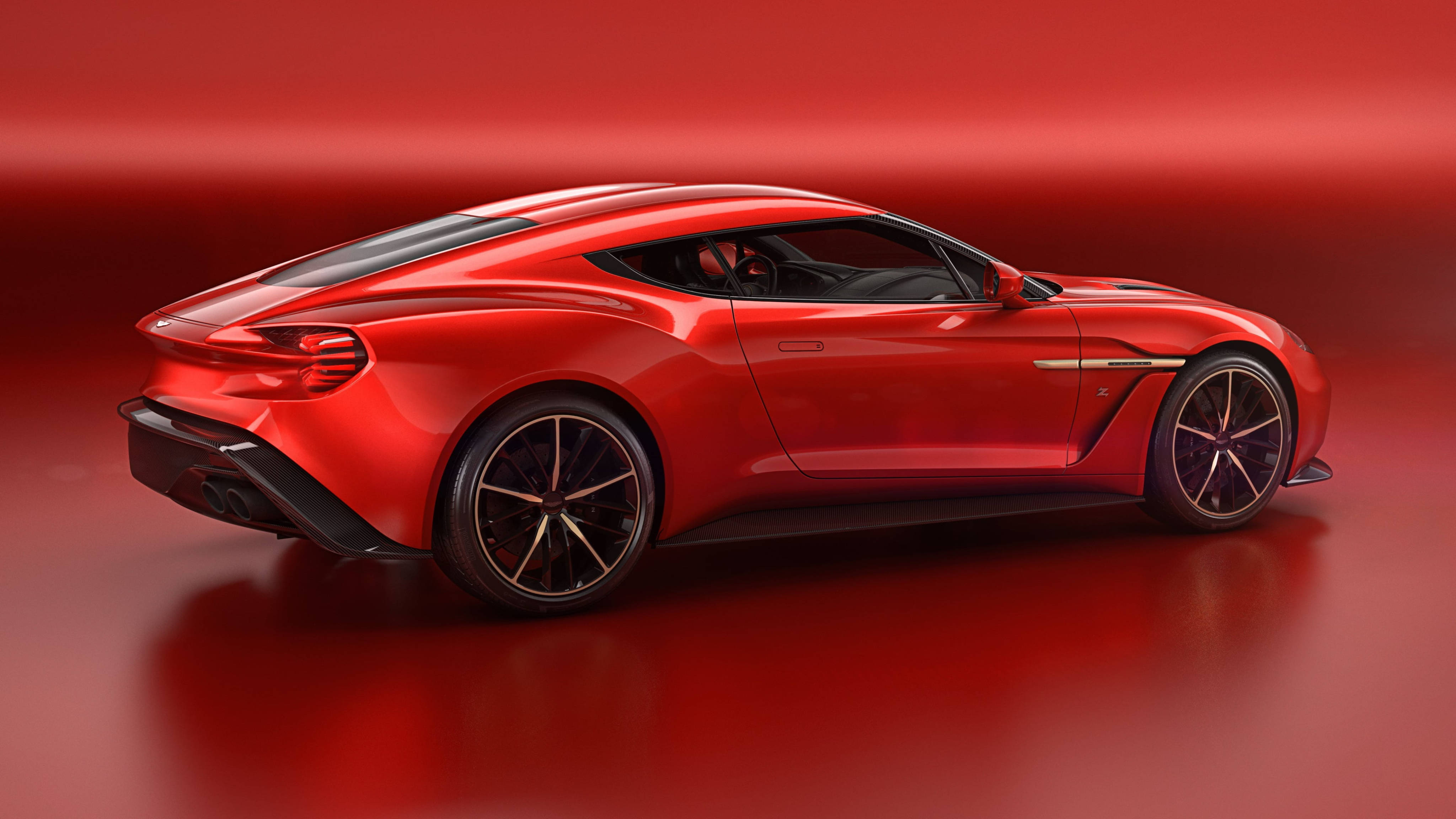 Vanquish Zagato 阿斯頓·馬丁 4K 壁紙 — 一輛帶有黑色裝飾的時尚紅色跑車，在攝影棚燈光下，映襯著相配的紅色漸變背景，閃閃發光。