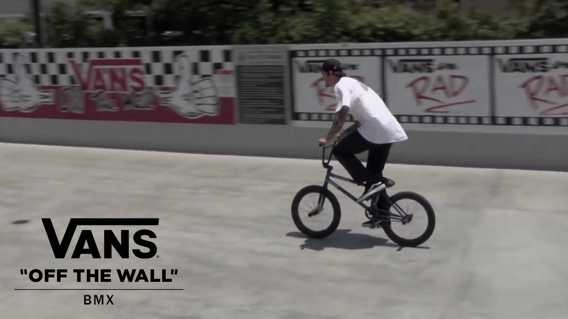 BMX車手在混凝土坡道上表演技巧，身後有Vans塗鴉牆。