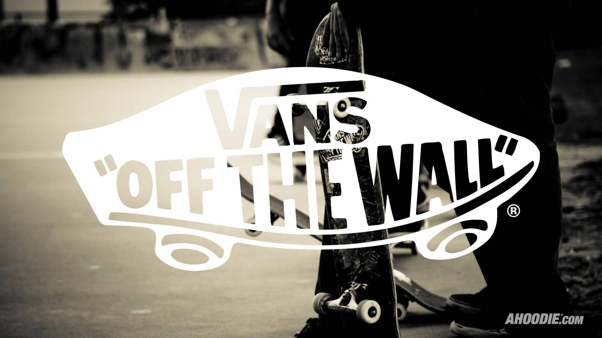 Vans Off The Wall 滑板少年 壁紙 — 一張棕褐色調的滑板特寫，大型Vans Off The Wall標誌覆蓋在一個人的腿和滑板上。