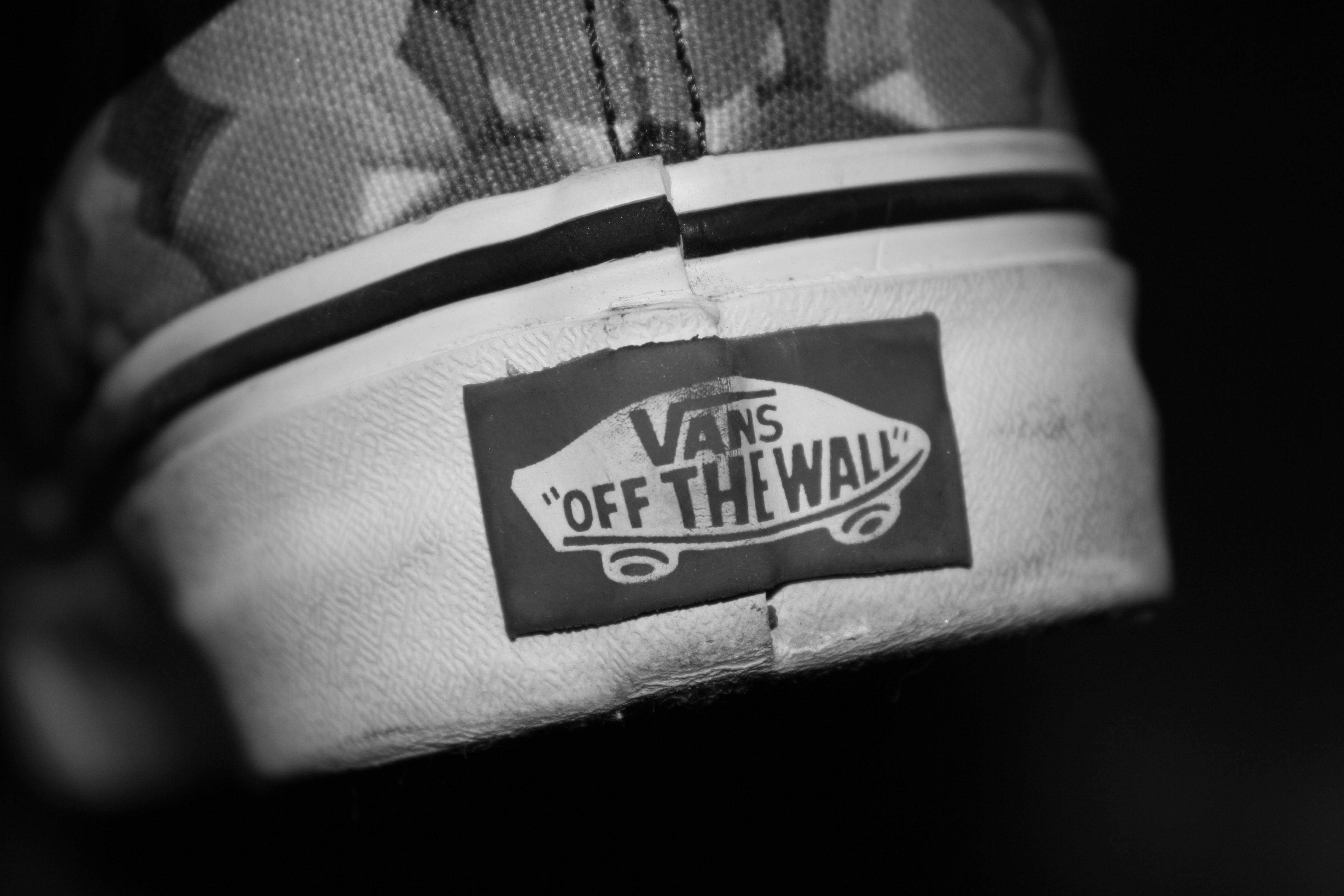 Vans Off The Wall 鞋款後視圖 壁紙 — 一對磨損帆布鞋上Vans運動鞋標誌性「Off The Wall」標籤的黑白特寫。