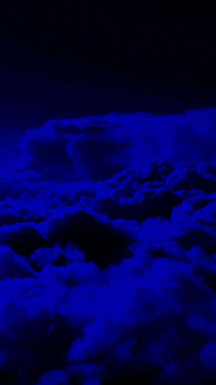  壁紙 — 廣闊的雲層在漆黑的天空下發出電光藍色，營造出超現實的夜晚氛圍。