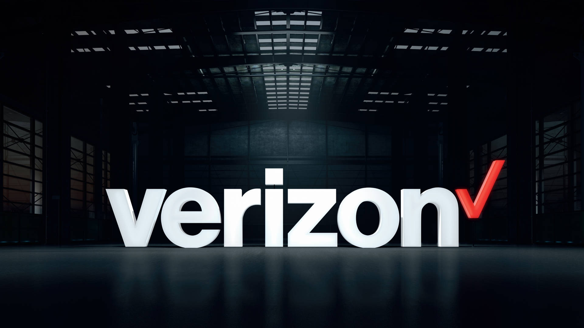 Verizon 2015 標誌 壁紙 — Verizon 標誌以粗體白色和紅色字母在黑暗的工業倉庫中突出顯示，倉庫有高天花板和天窗。