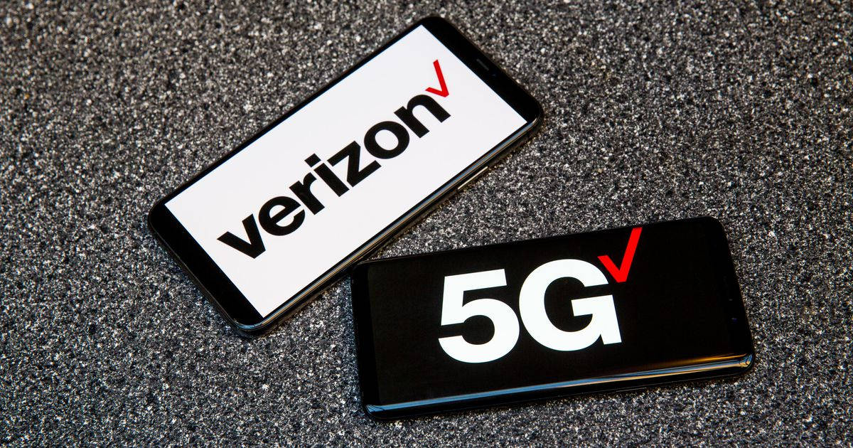 Verizon 5G 手機上網 壁紙 — 兩部顯示Verizon和5G標誌的智能手機放在有紋理的灰色表面上。