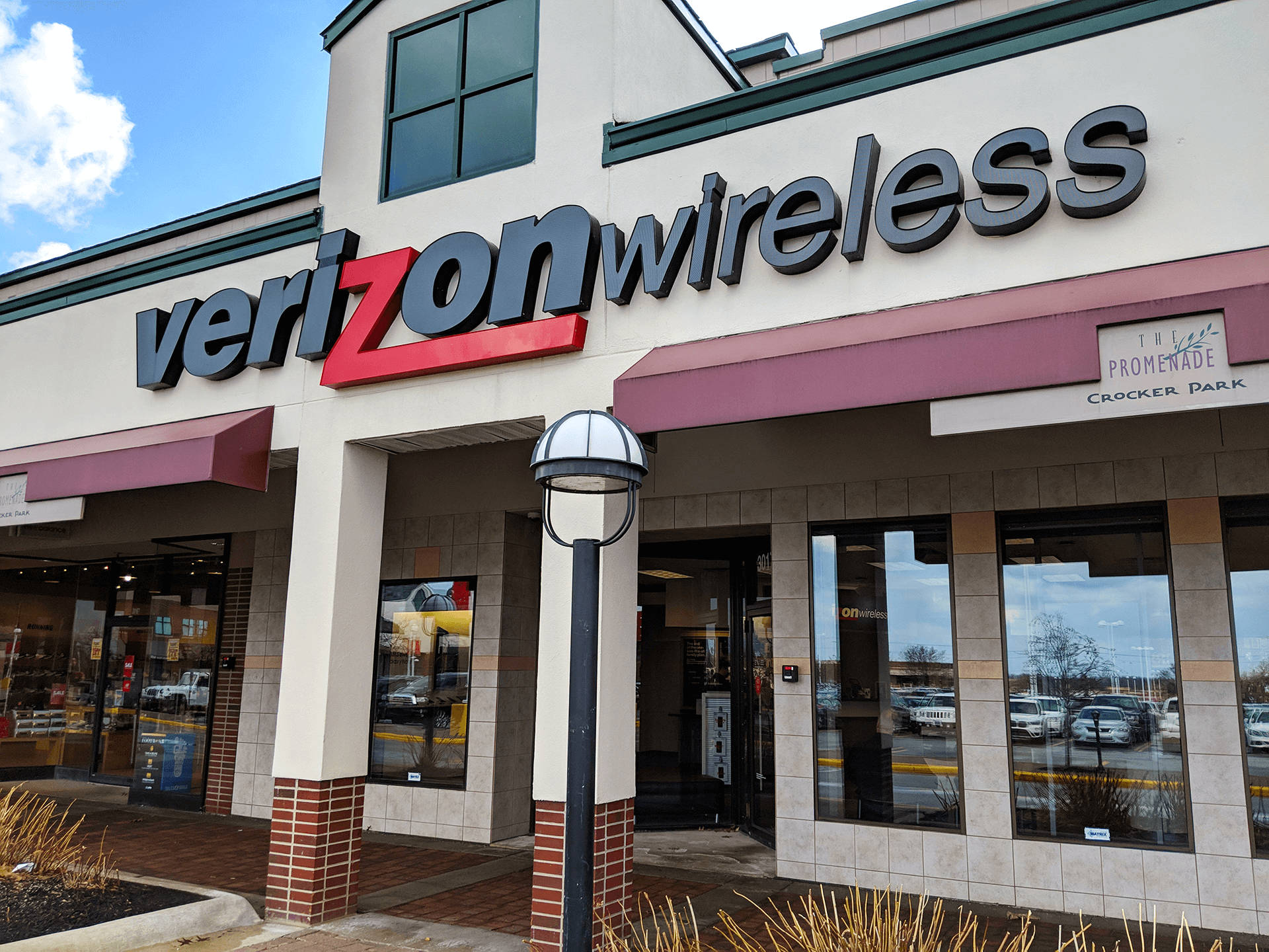 Verizon無線克羅克公園店 壁紙 — Verizon Wireless 店舖外觀，在晴朗藍天和零星白雲下，設有醒目的紅色和灰色招牌。