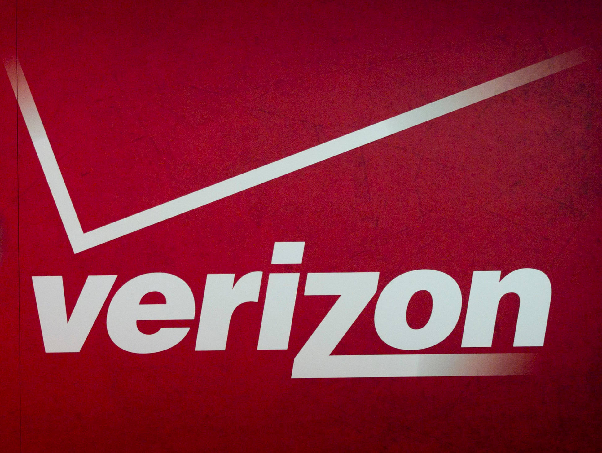 Verizon 古典紅色標誌 壁紙 — 一個大膽的白色Verizon標誌，帶有對角線，位於有紋理的深紅色背景上。