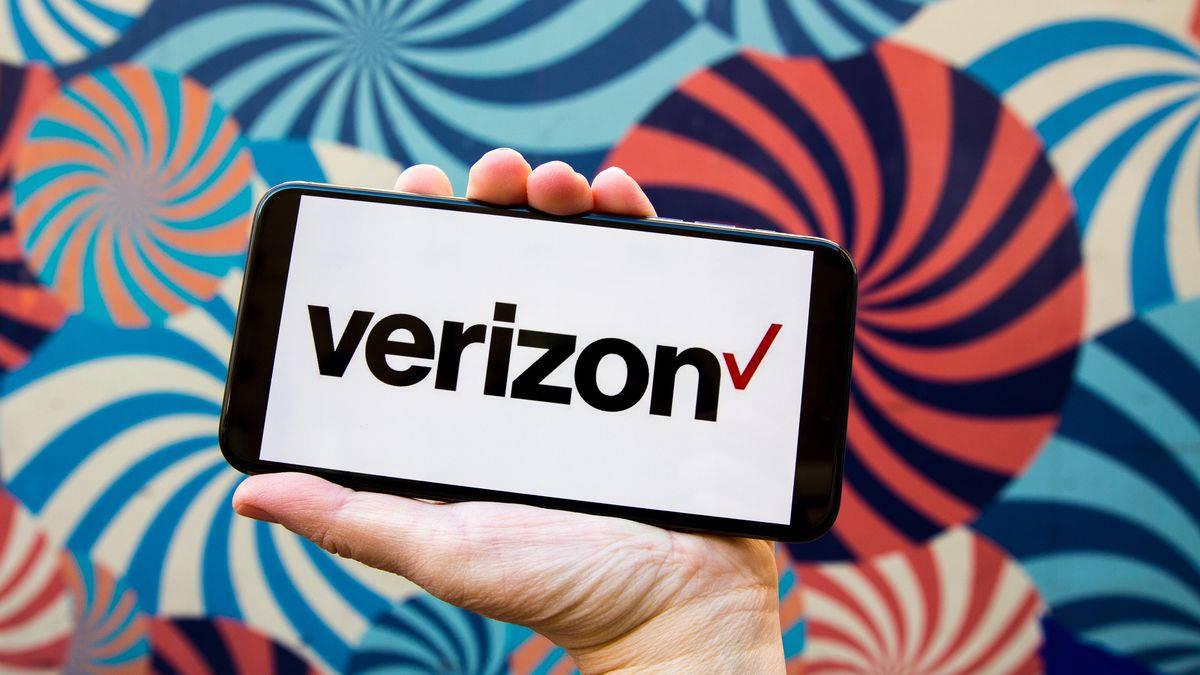 Verizon標誌與科技 壁紙 — 一隻手拿著一部顯示Verizon標誌的智能手機，背景是充滿活力的漩渦圖案牆壁。