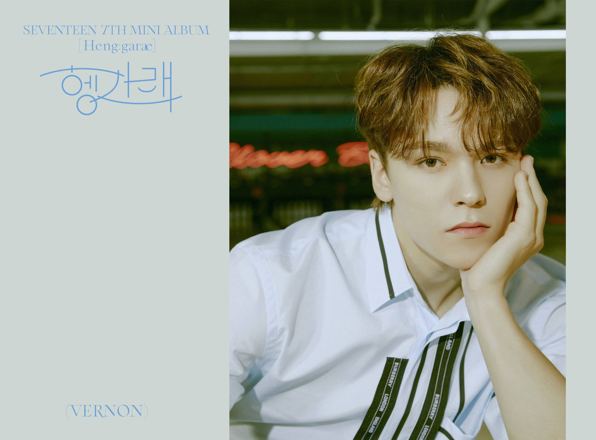 Vernon Heng Garae 單曲海報 壁紙 — 一個棕色亂髮的年輕男子，穿著帶黑色條紋的白襯衫，手托下巴，背景柔和模糊。
