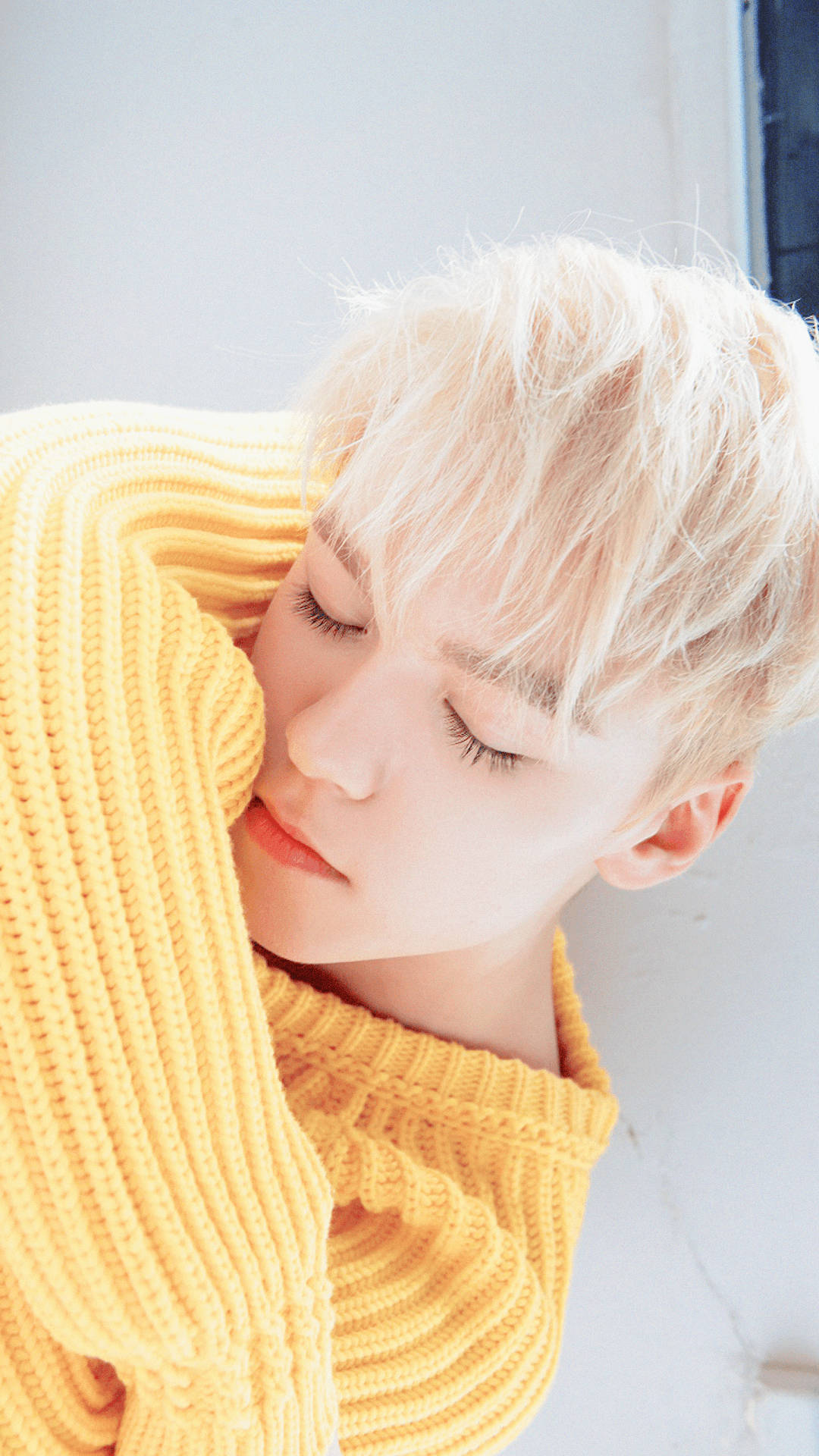 Vernon 睡眠時刻 壁紙 — 一位擁有鉑金色頭髮的人，穿著亮黃色羅紋毛衣，靠著柔軟的白色牆壁平靜地休息。