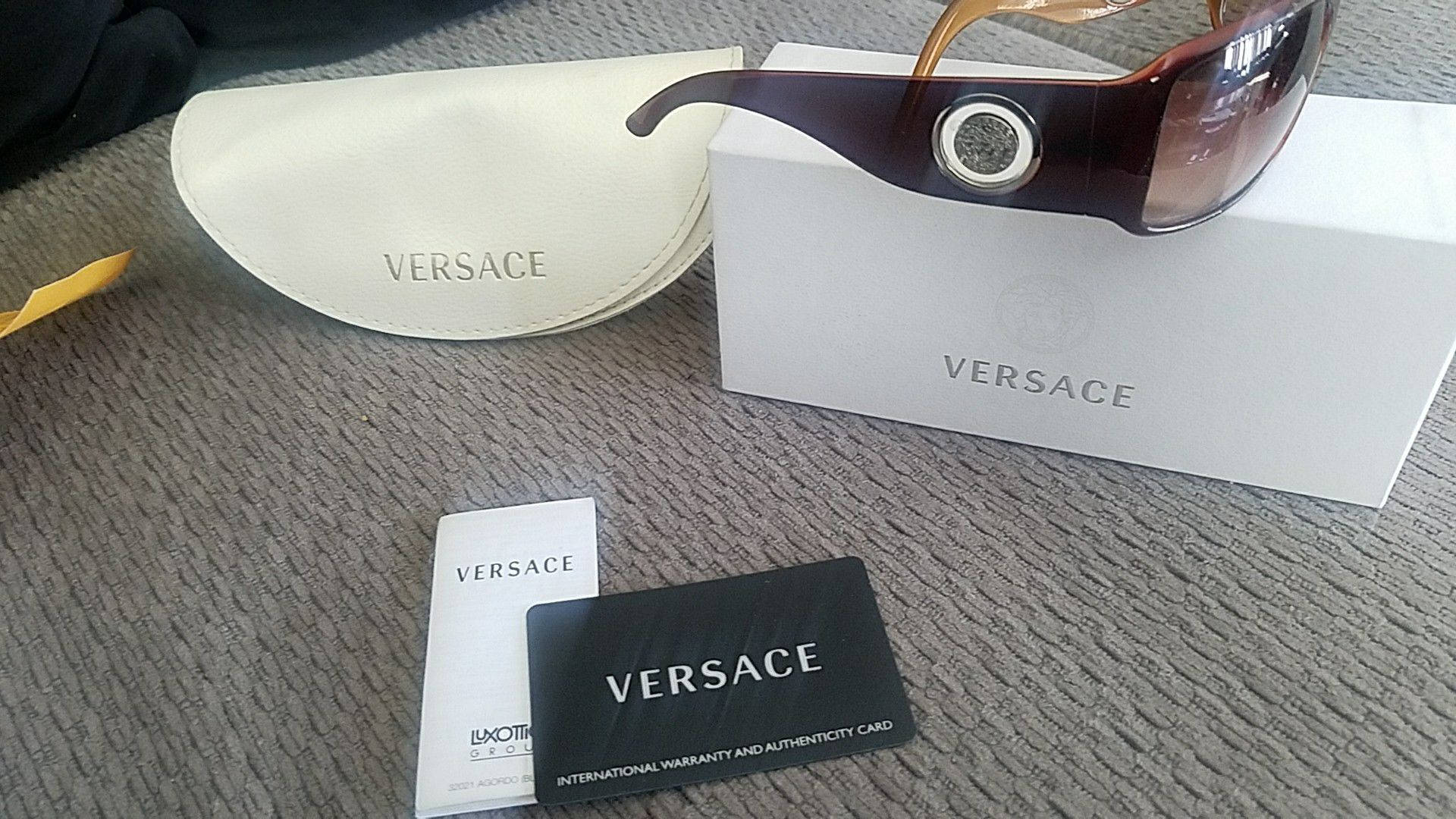 Versace VE4044 太陽眼鏡禮盒 壁紙 — 奢華 Versace 太陽眼鏡放置在帶有紋理的灰色表面上，位於品牌包裝之上。