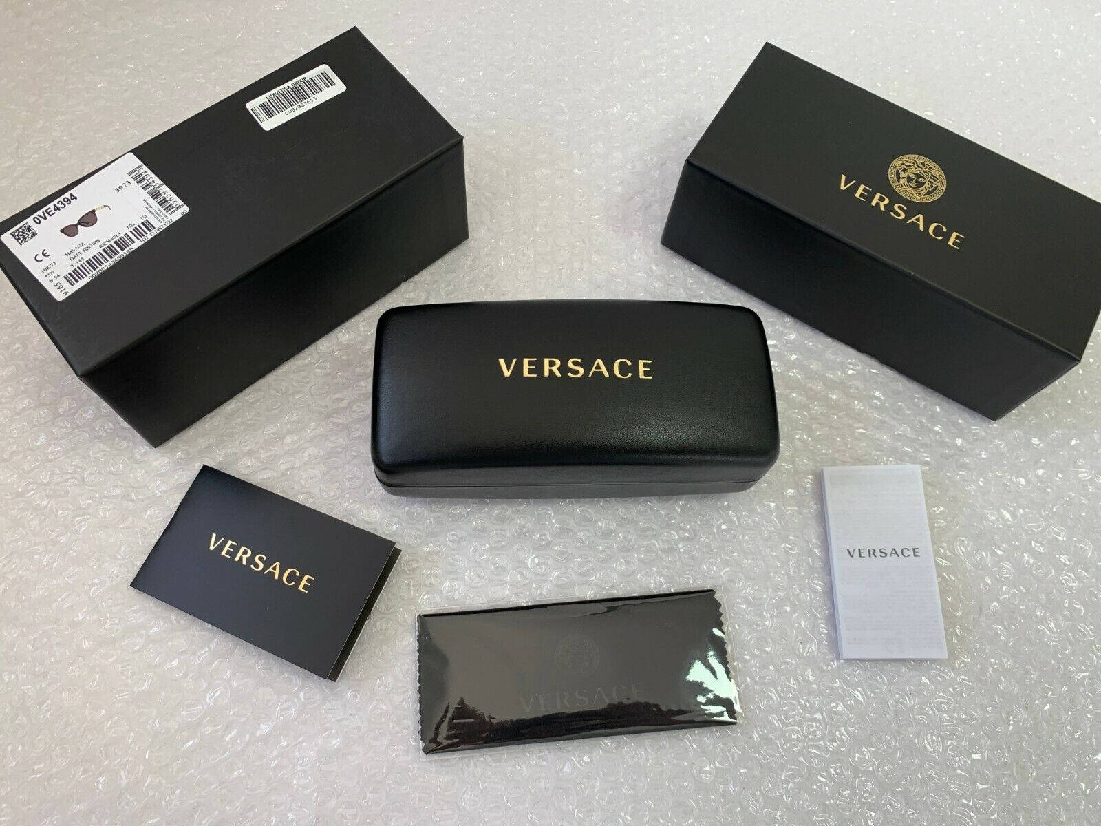 Versace硬殼鏡盒 壁紙 — 奢華Versace太陽眼鏡包裝放置在氣泡紙上，包括盒子、眼鏡盒、眼鏡布和小冊子。