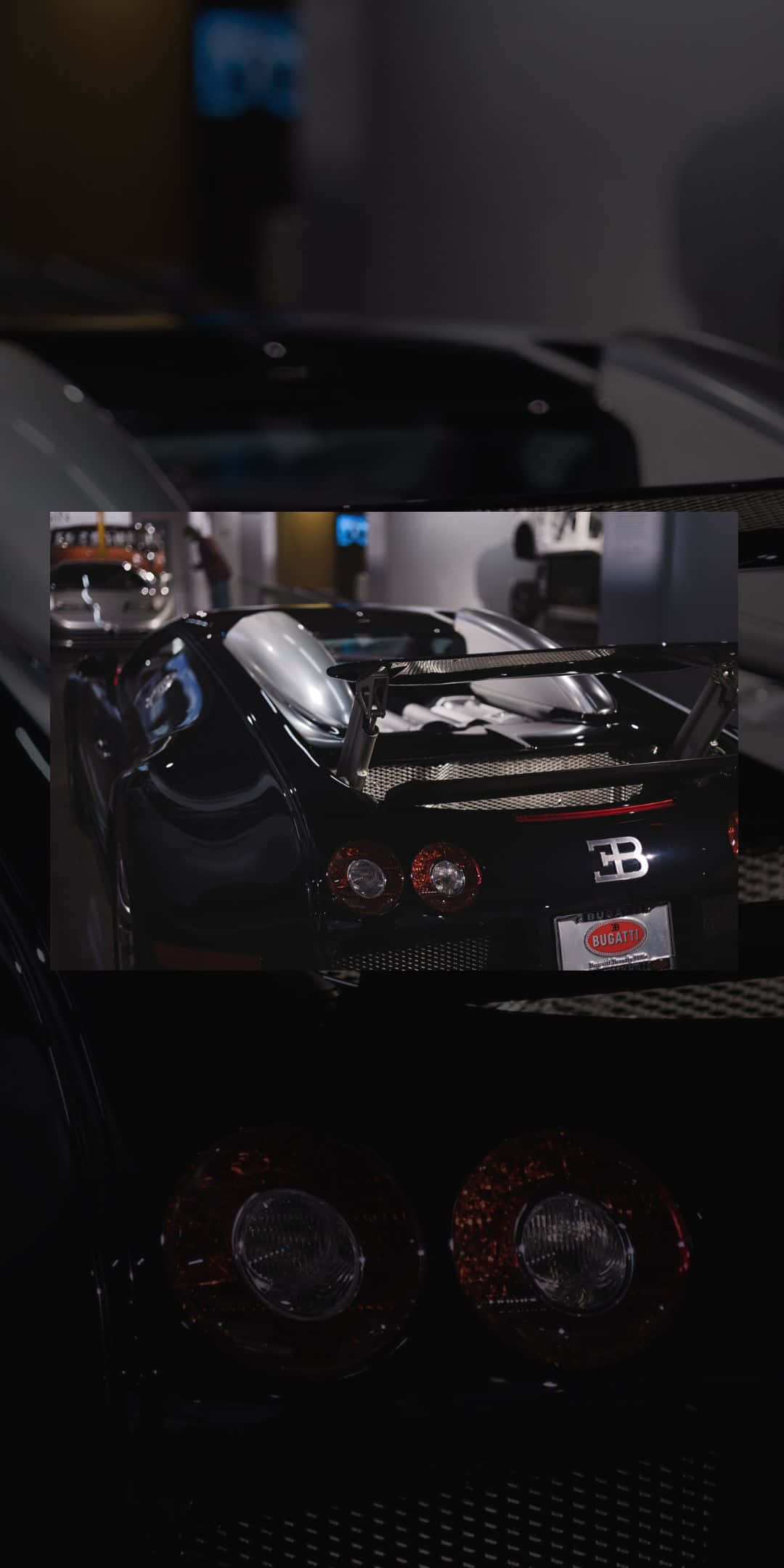 Veyron 後視圖 Pixel 3 布加迪背景 壁紙 — 一輛時尚的黑色Bugatti超級跑車在昏暗的展廳燈光下閃耀，展示其標誌性的後翼和發光的尾燈。