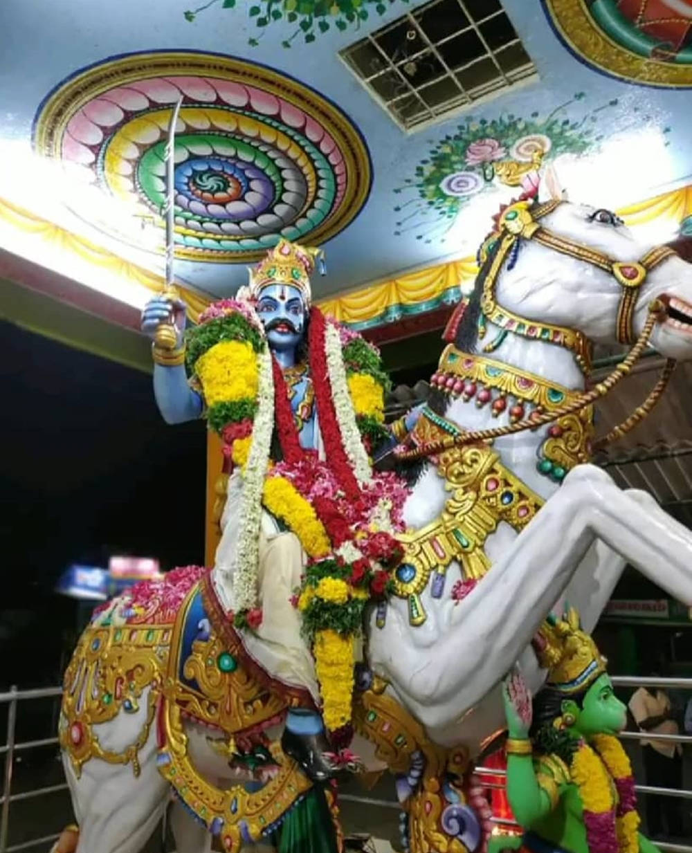 藍色神祇騎著白馬，帶有金色裝飾和花環，在夜晚中。 — 馬 壁紙