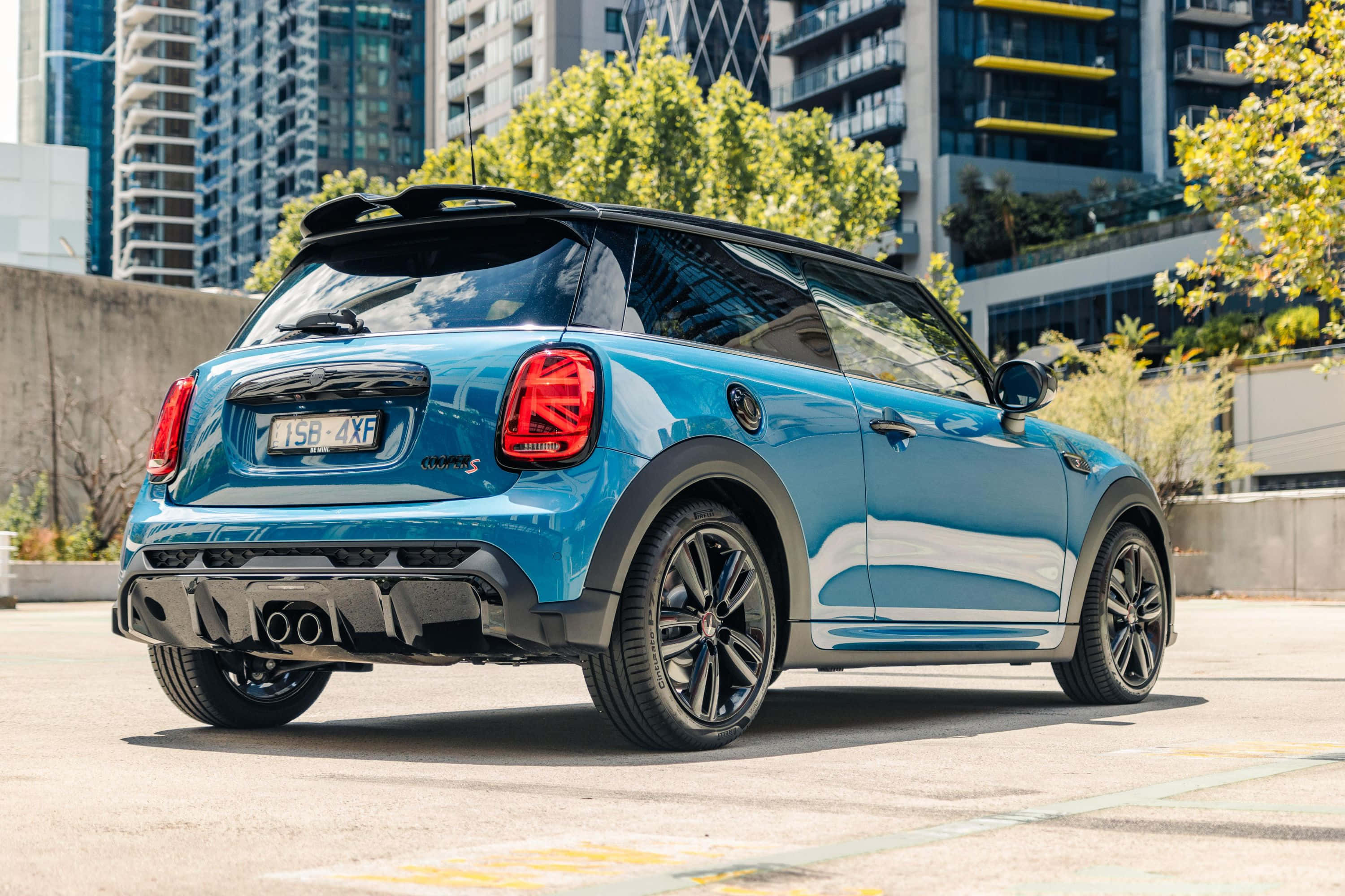 Mini Cooper S 桌布 壁紙 — 一輛充滿活力的藍色MINI Cooper停泊在城巿街道上，背景有現代建築和綠樹。