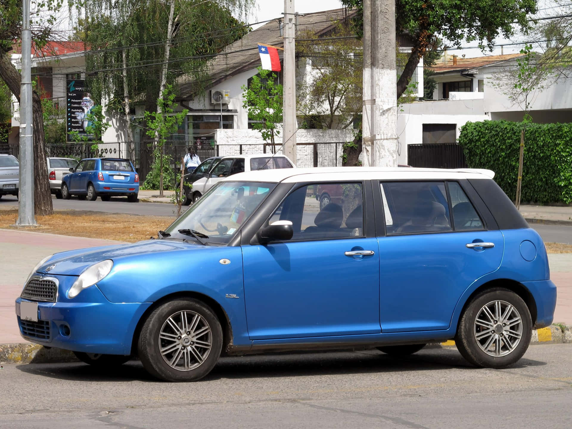  壁紙 — 一輛鮮藍色白色車頂嘅Mini Cooper停泊喺陽光普照、兩旁種滿樹木同房屋嘅城市街道上。