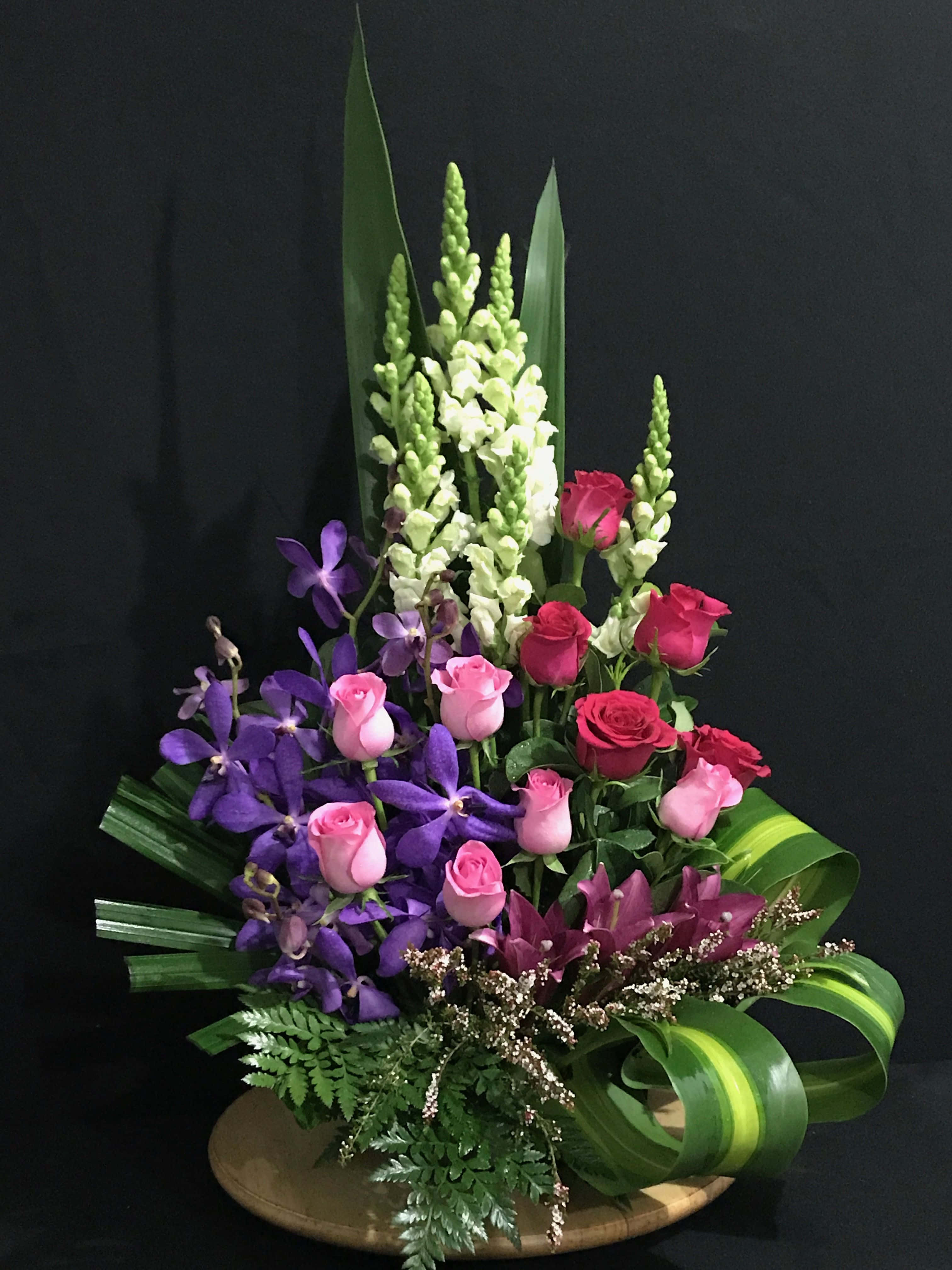 Flower Arrangement 桌布 壁紙 — 充滿活力的花卉佈置，紫色蘭花、粉紅玫瑰和白色穗狀花在純黑背景下格外突出。