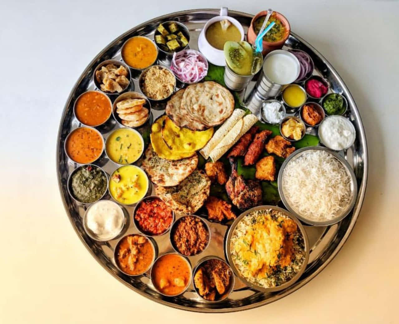 Thali 桌布 壁紙 — 一個充滿活力的印度塔利拼盤，色彩繽紛的咖喱、麵包、米飯和酸辣醬整齊排列在閃亮的金屬托盤上。