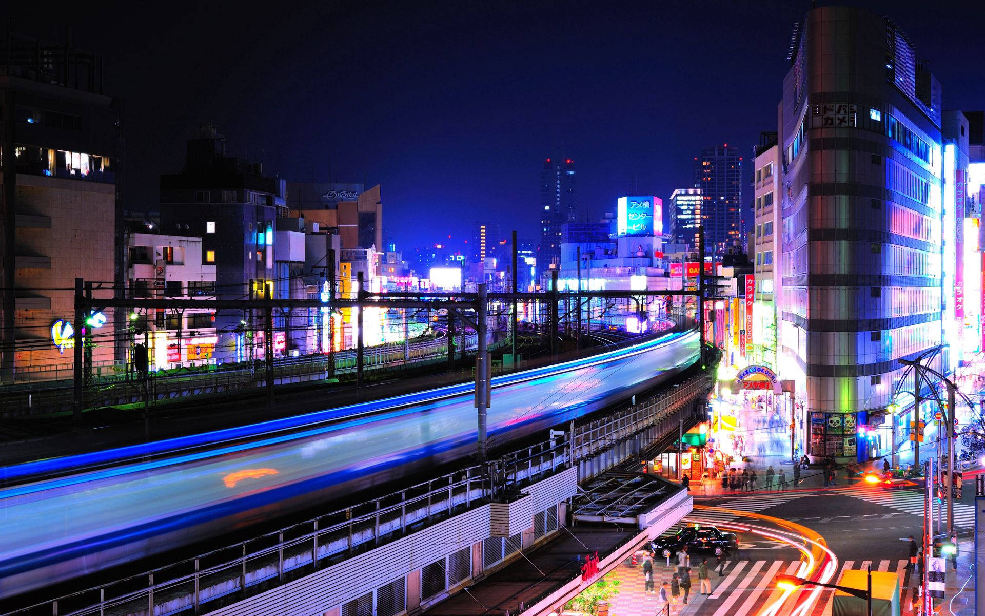 日本の東京の鉄道 壁紙 — 充滿活力的夜間城市景觀，霓虹燈和火車運動模糊照亮繁華的城市街道。