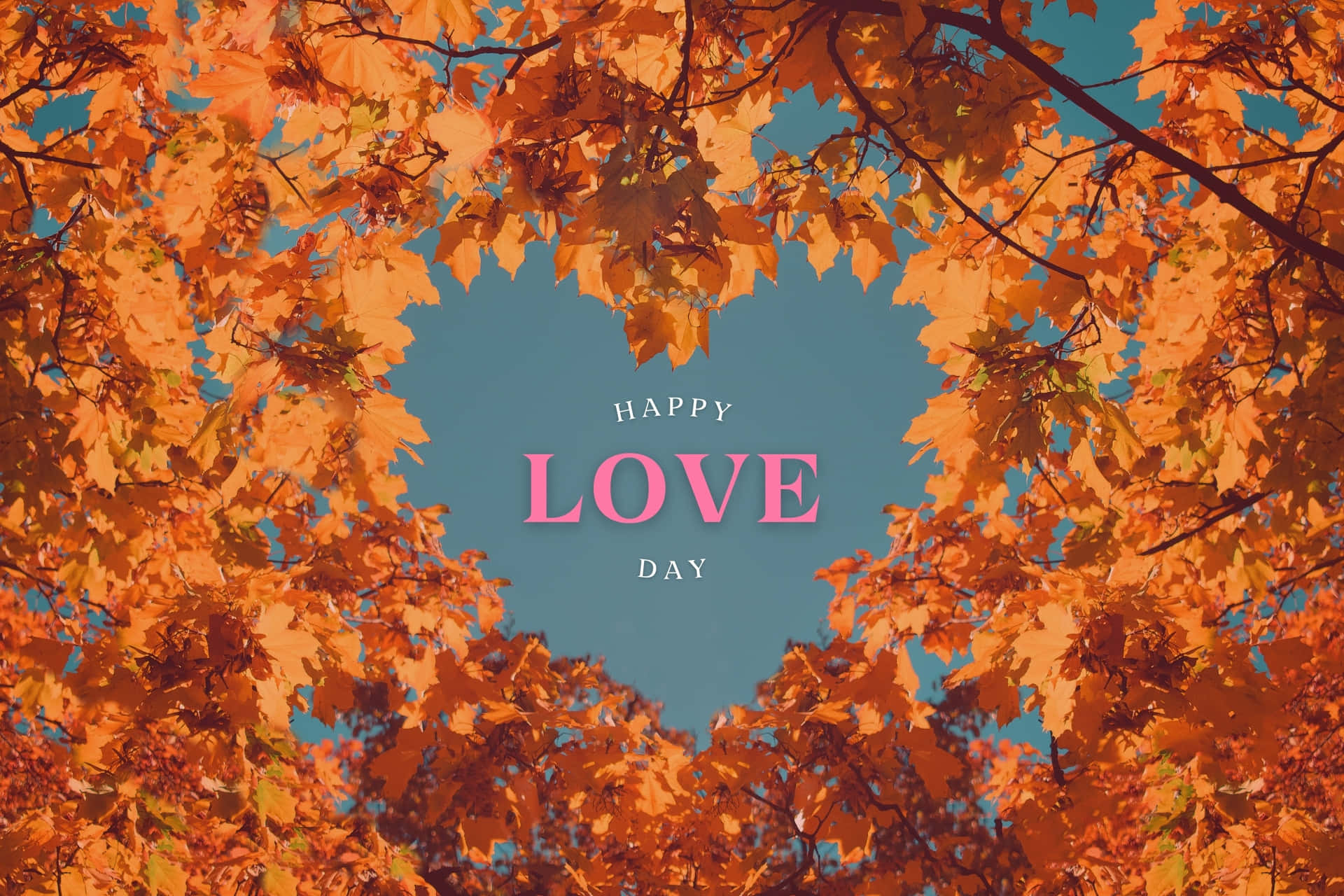  壁紙 — 鮮豔的橙色秋葉形成心形，框住藍天，並帶有粉紅色「LOVE」文字。
