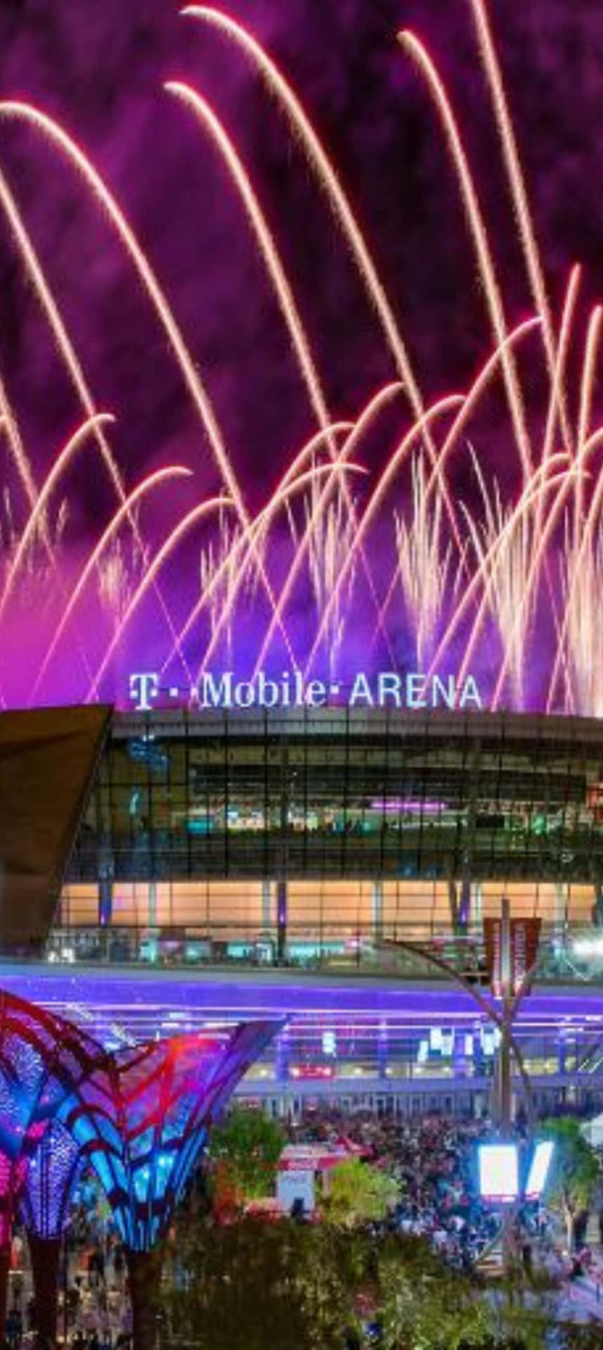  壁紙 — 充滿活力的紫色和金色煙火在燈火通明的T-Mobile Arena上空爆炸，人群在無星的夜空下聚集在下方。