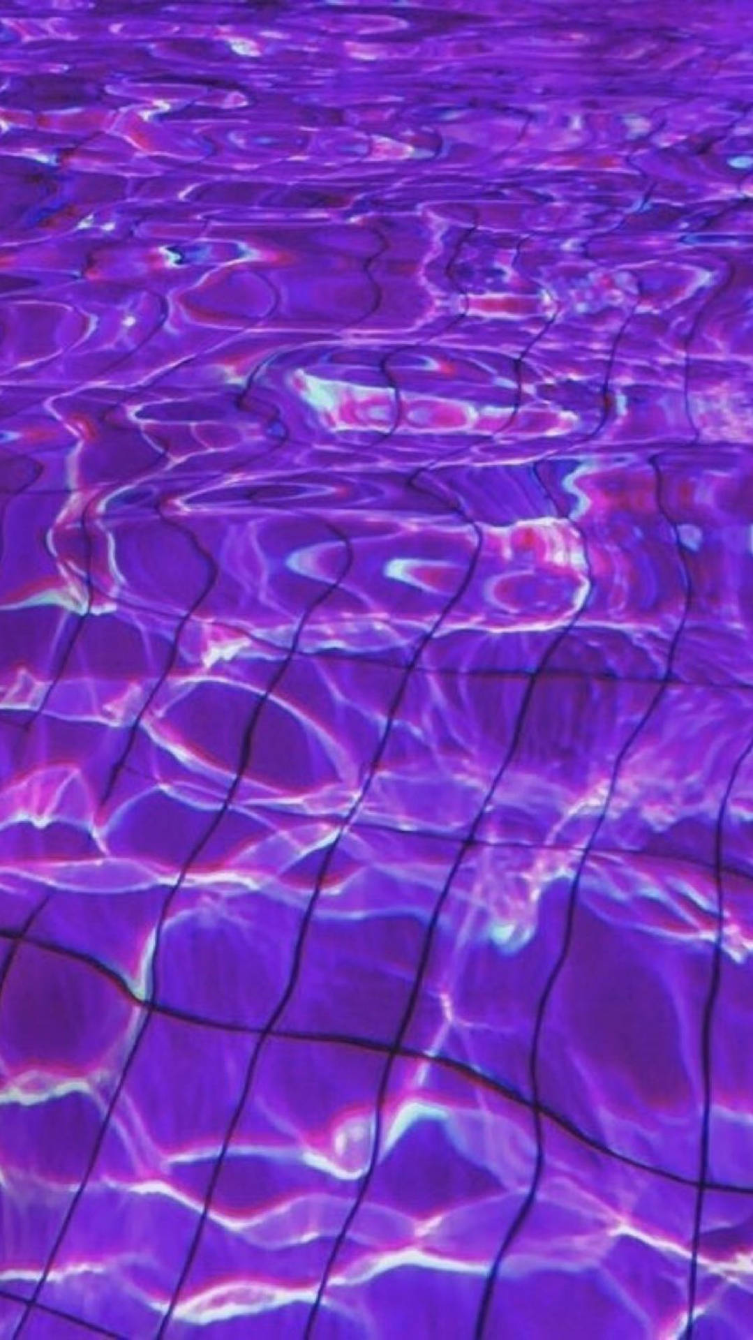 紫色水波紋在瓷磚泳池地板上閃爍著電燈反射的光芒。